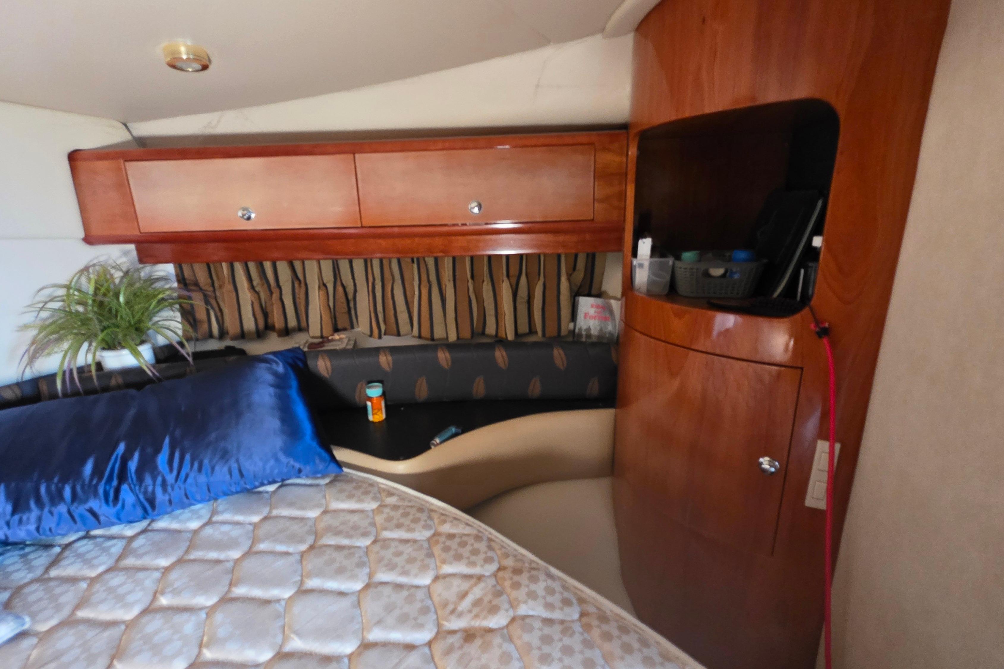 Interior of 2002 Regal Commodore 4260 yacht with wooden cabinets and cozy bedding.
