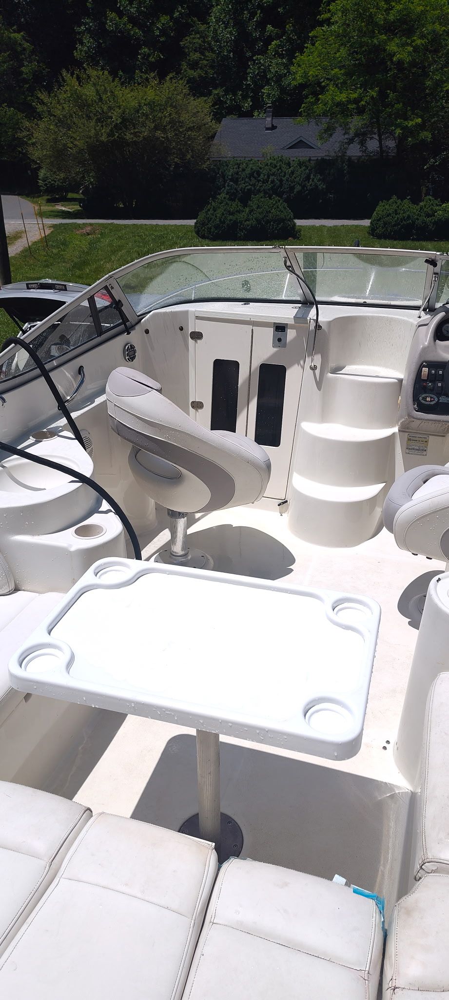 The image shows the cockpit of a 2002 Stingray 240 CR boat with white seats and a table.