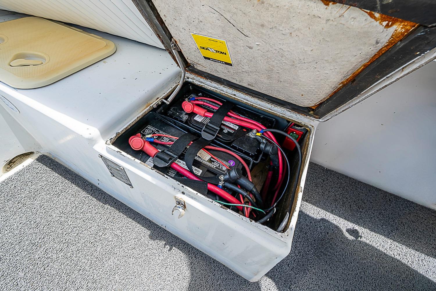 Open battery compartment in a 1969 custom vehicle, showing wiring and connections.