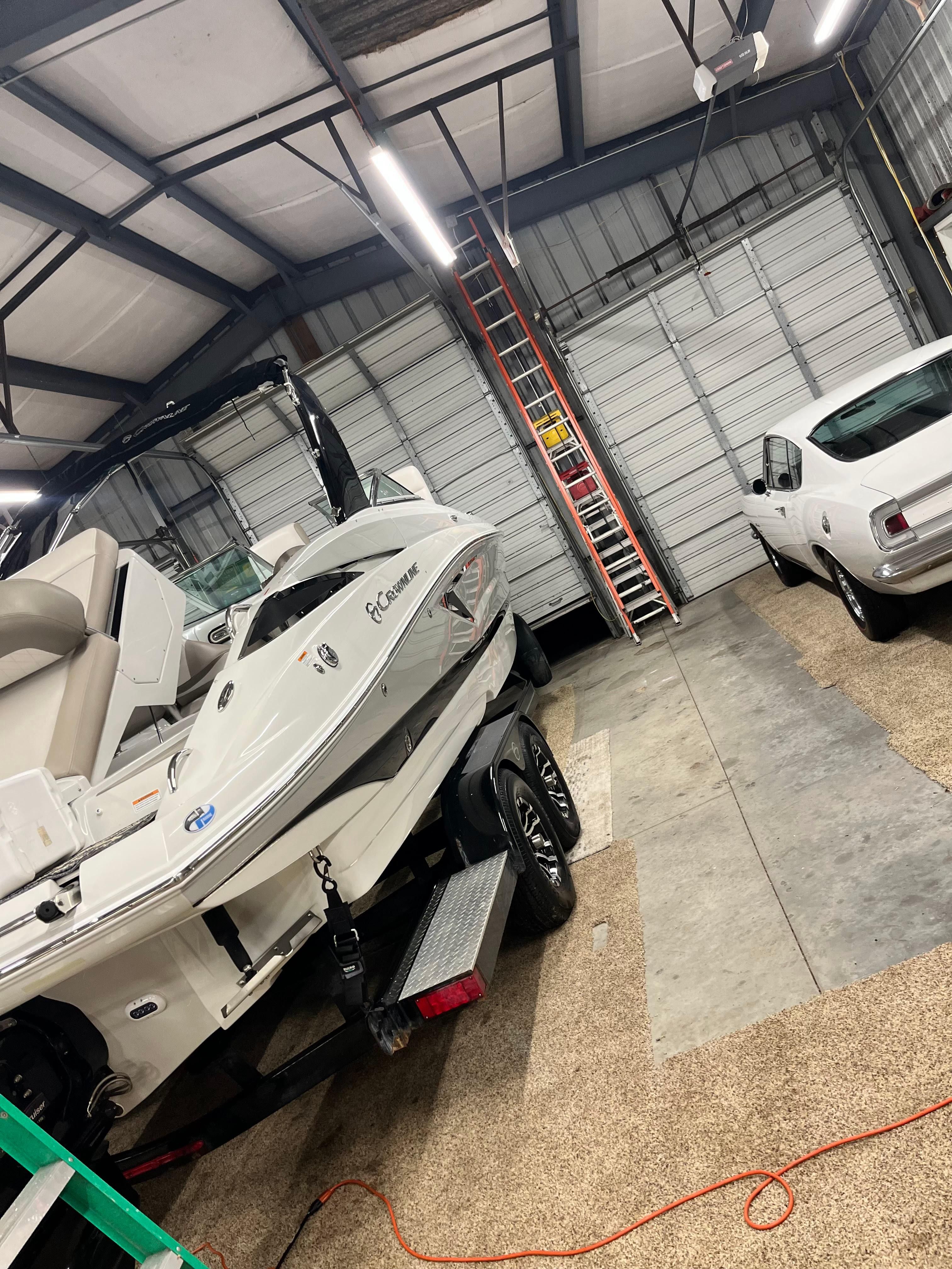 A 2019 Crownline E 285 boat is in a garage next to a white car.