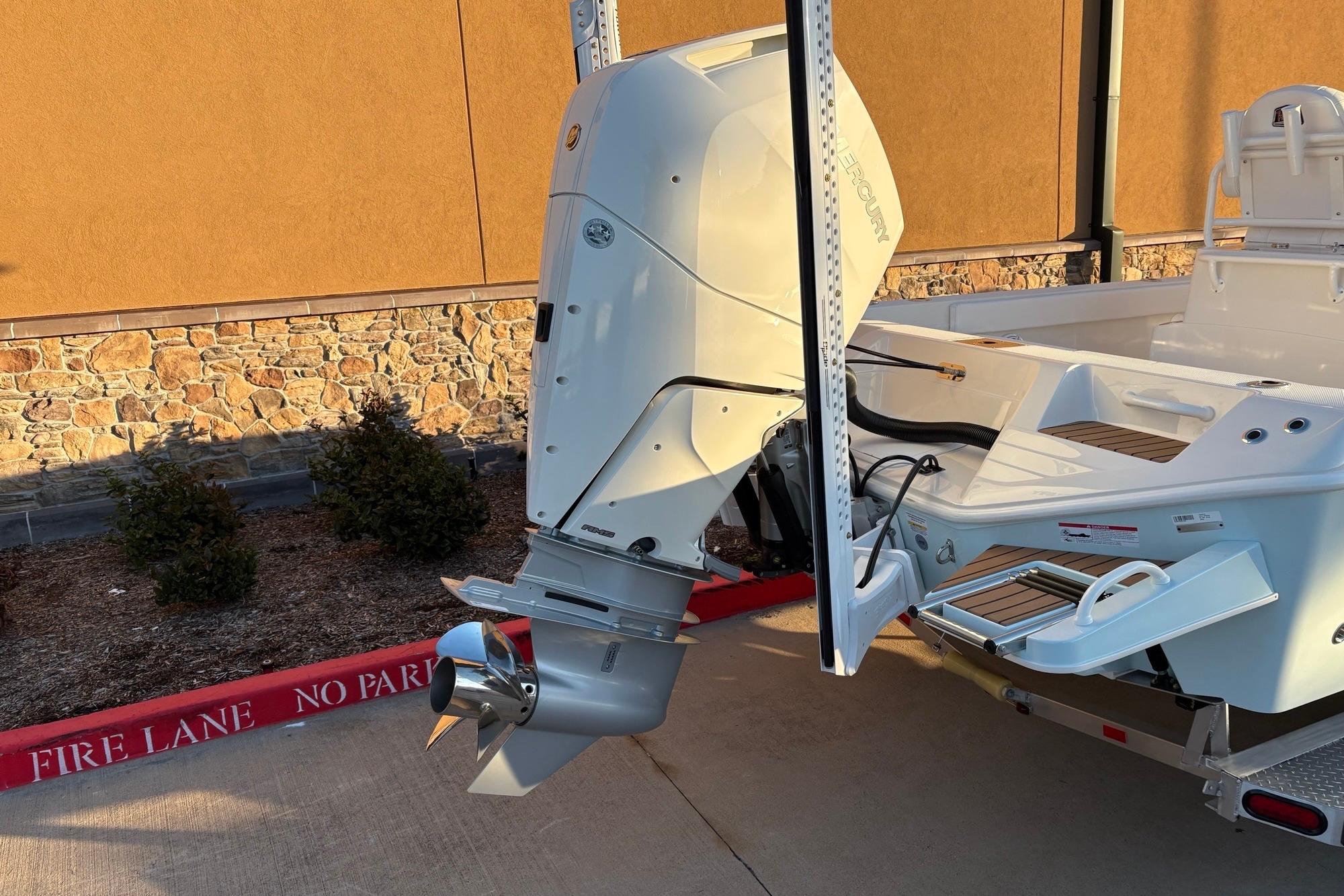 2026 Ranger 2660 Bay boat with powerful outboard motor, parked near a stone wall.