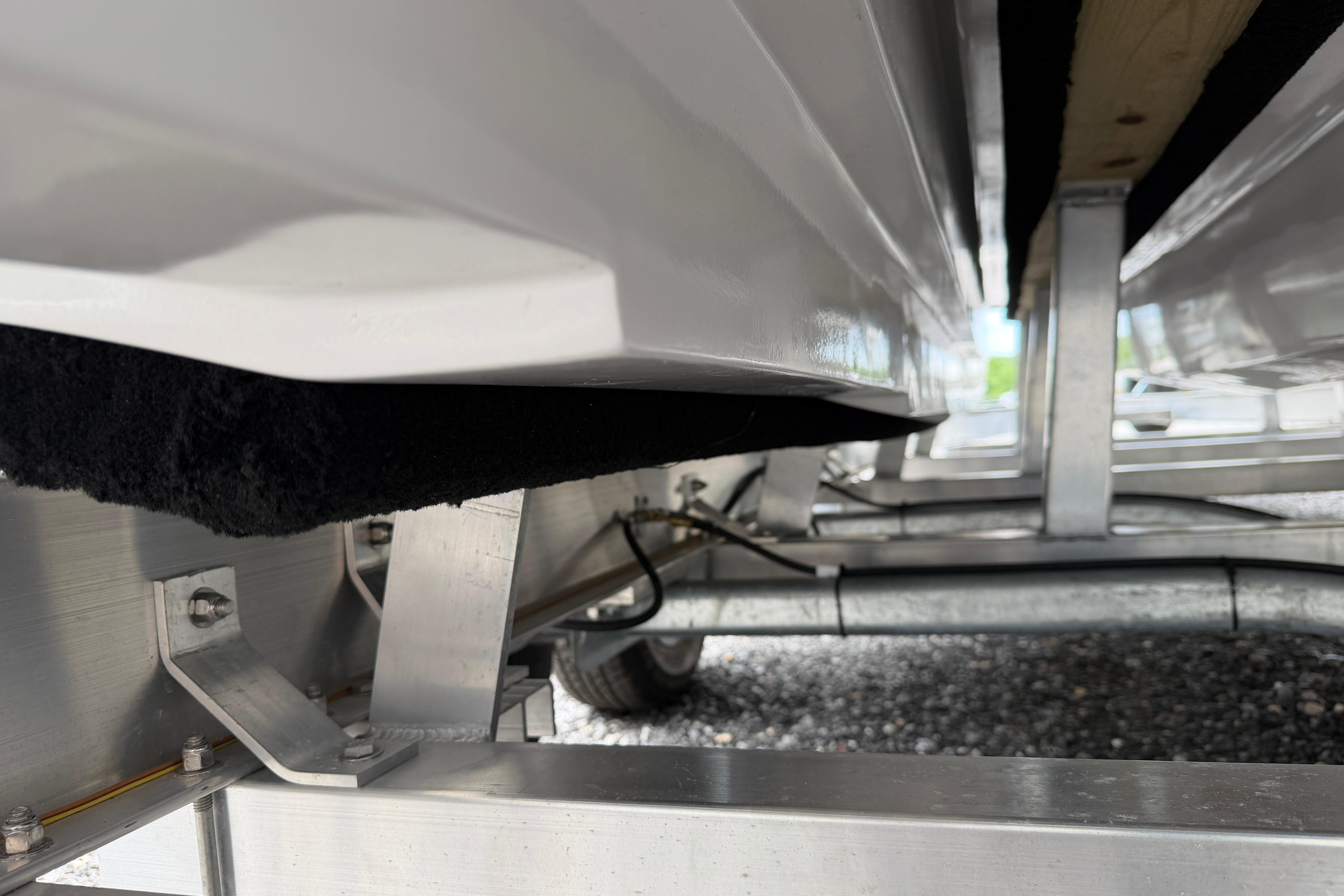Underside view of 2026 Skuta 24 Cat boat trailer, showcasing metal framework.