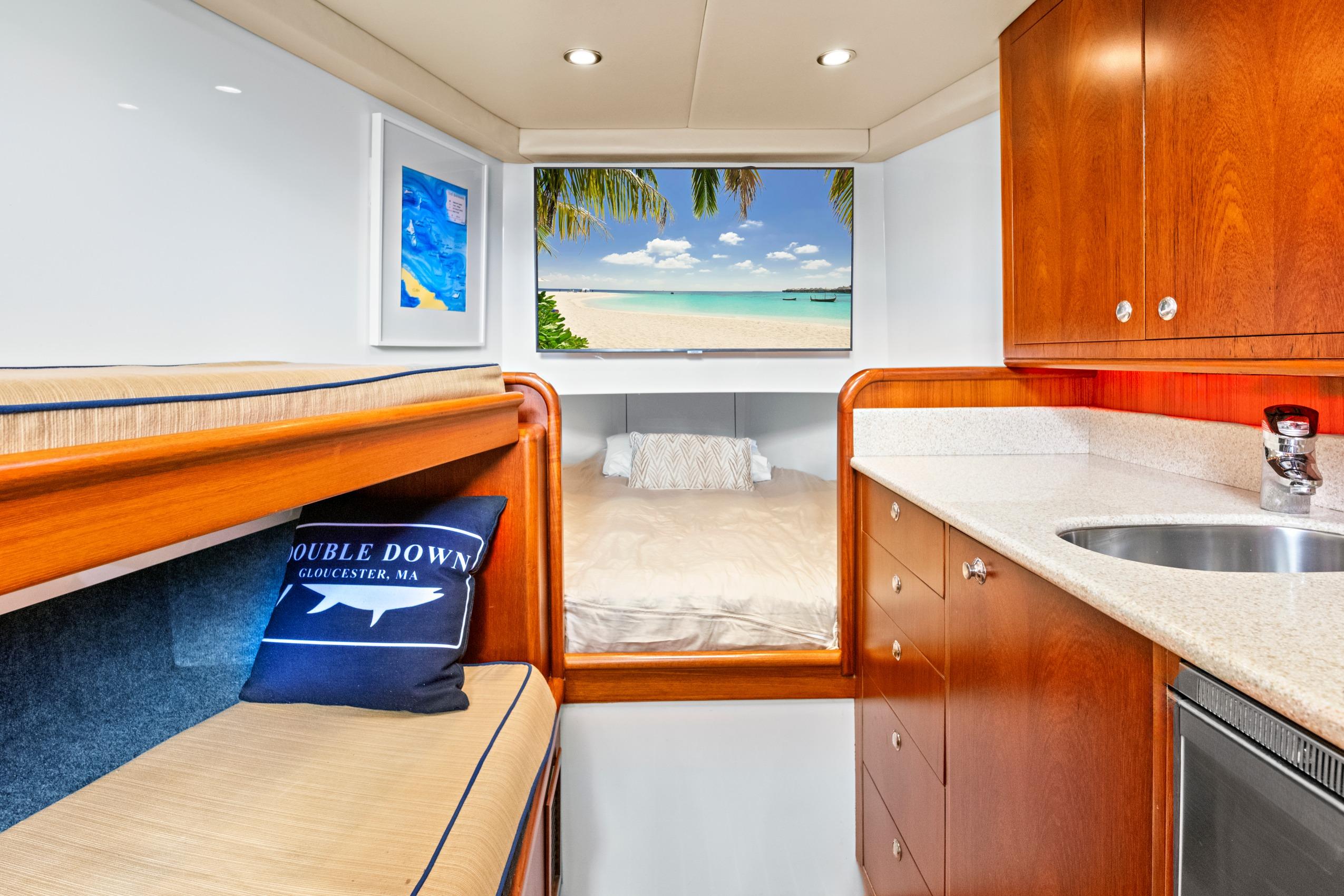 Luxurious yacht interior with wood cabinetry, cozy bed, and scenic beach view.
