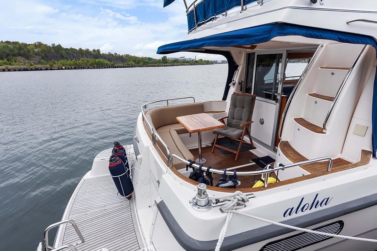 Nimbus 380 Carisma 2000 yacht with outdoor seating, docked by a scenic waterway.