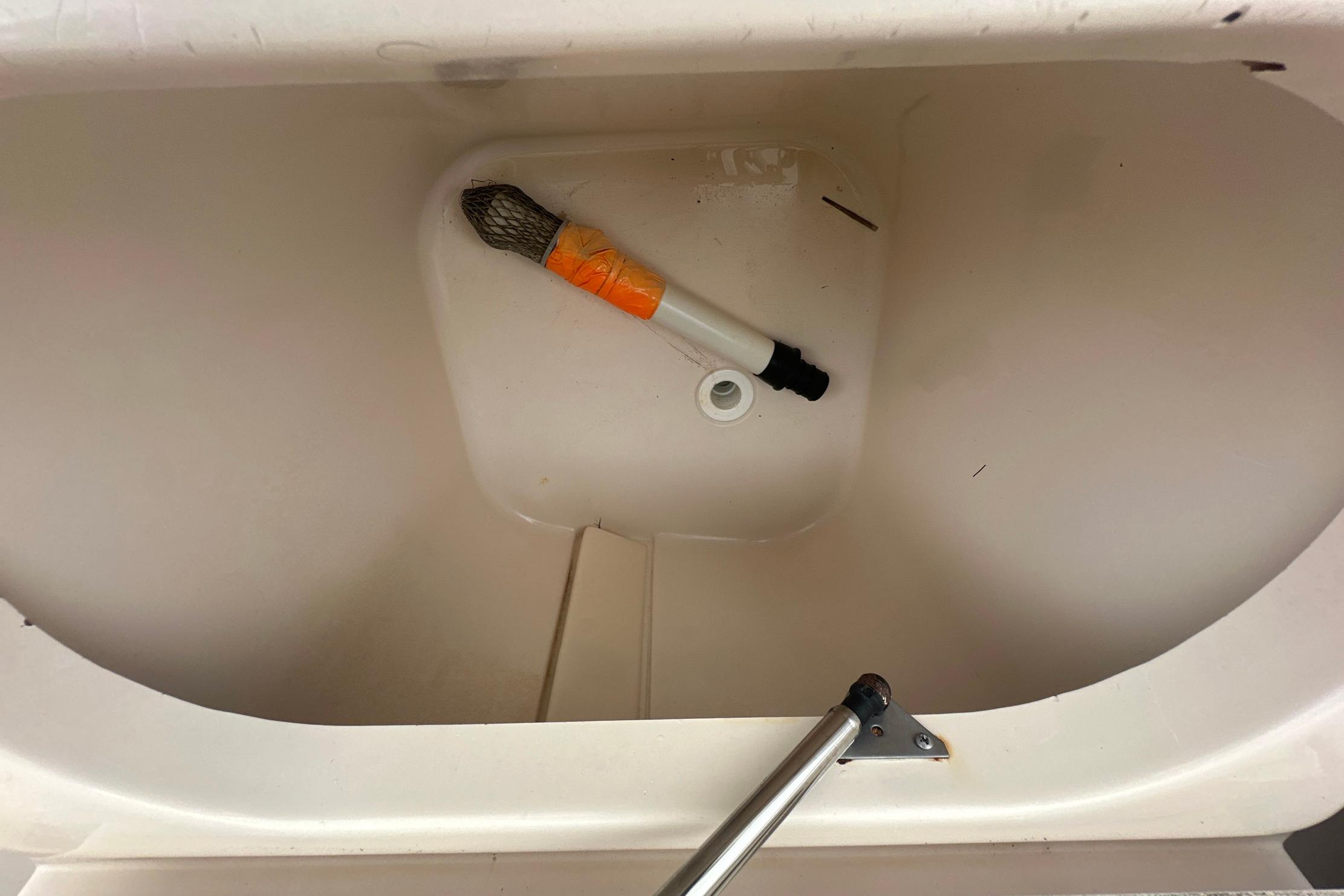 Storage compartment of a 2006 Grady-White Marlin 300 boat with a brush inside.