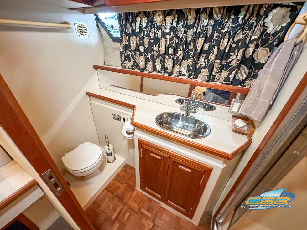 1989 Carver 3807 Aft Cabin bathroom with sink, toilet, and floral curtains.