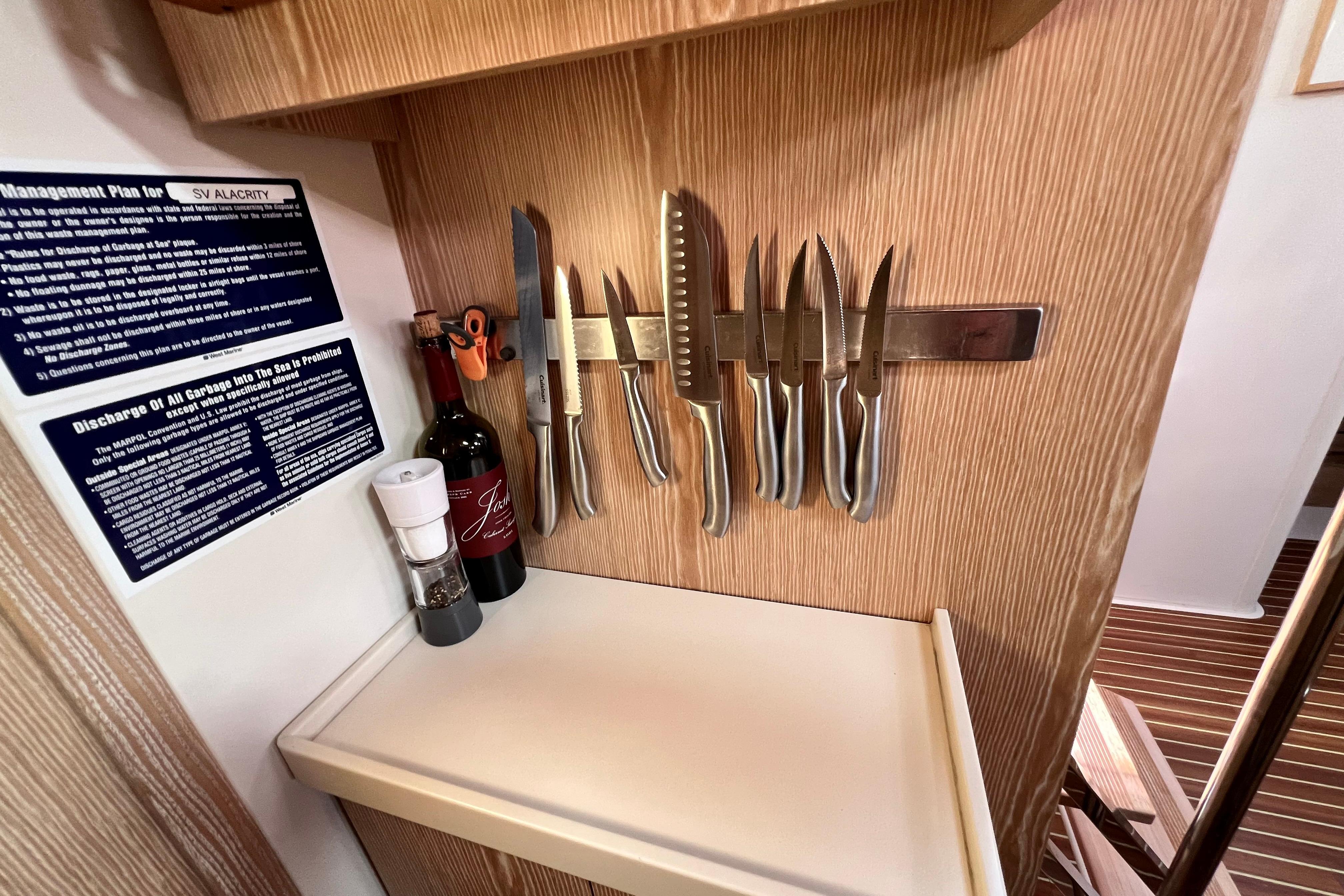 Kitchen area on a 2016 Hanse 455 yacht with knives and wine bottle.