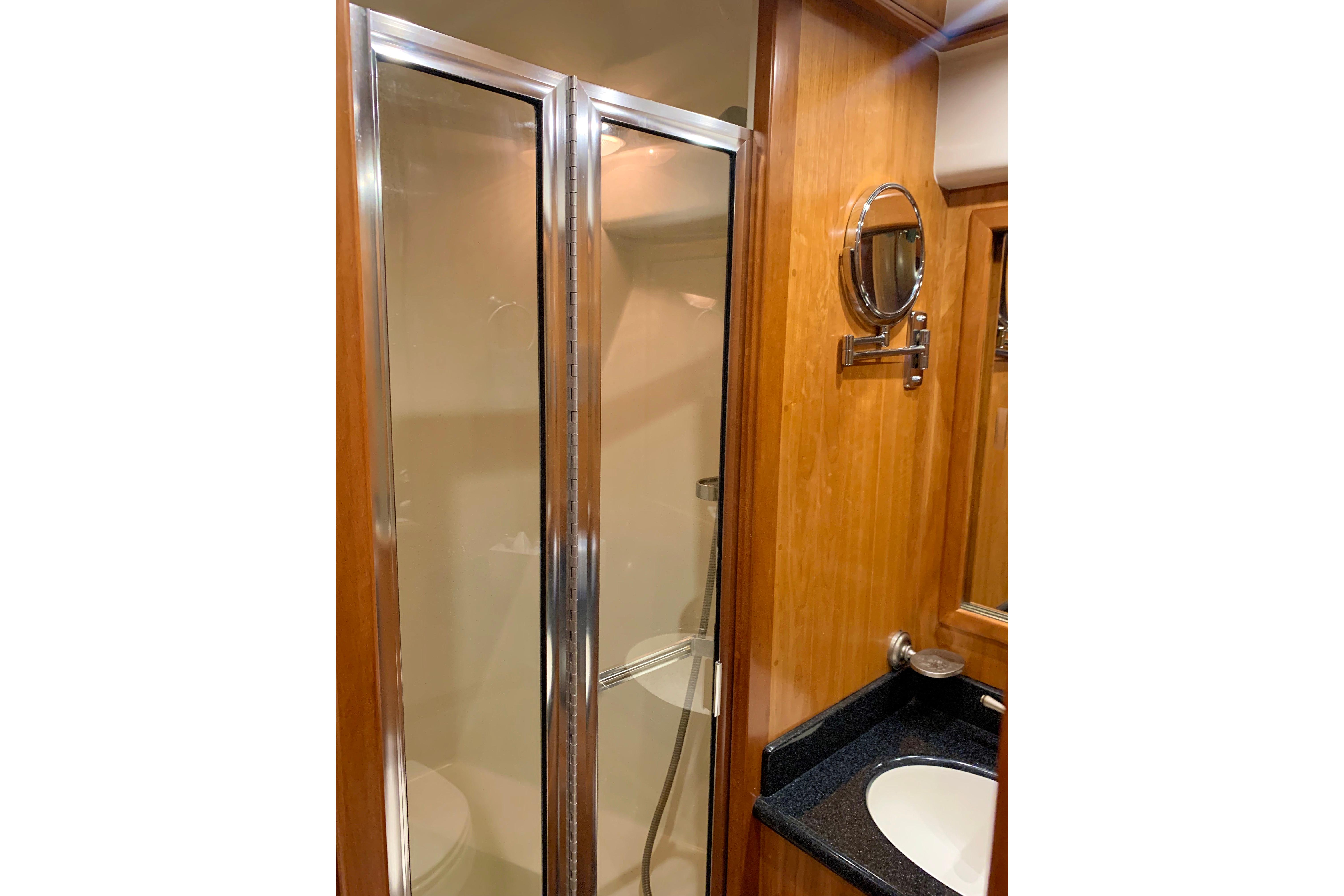 Luxurious bathroom in 2007 Navigator 5100 yacht with glass shower and wooden accents.