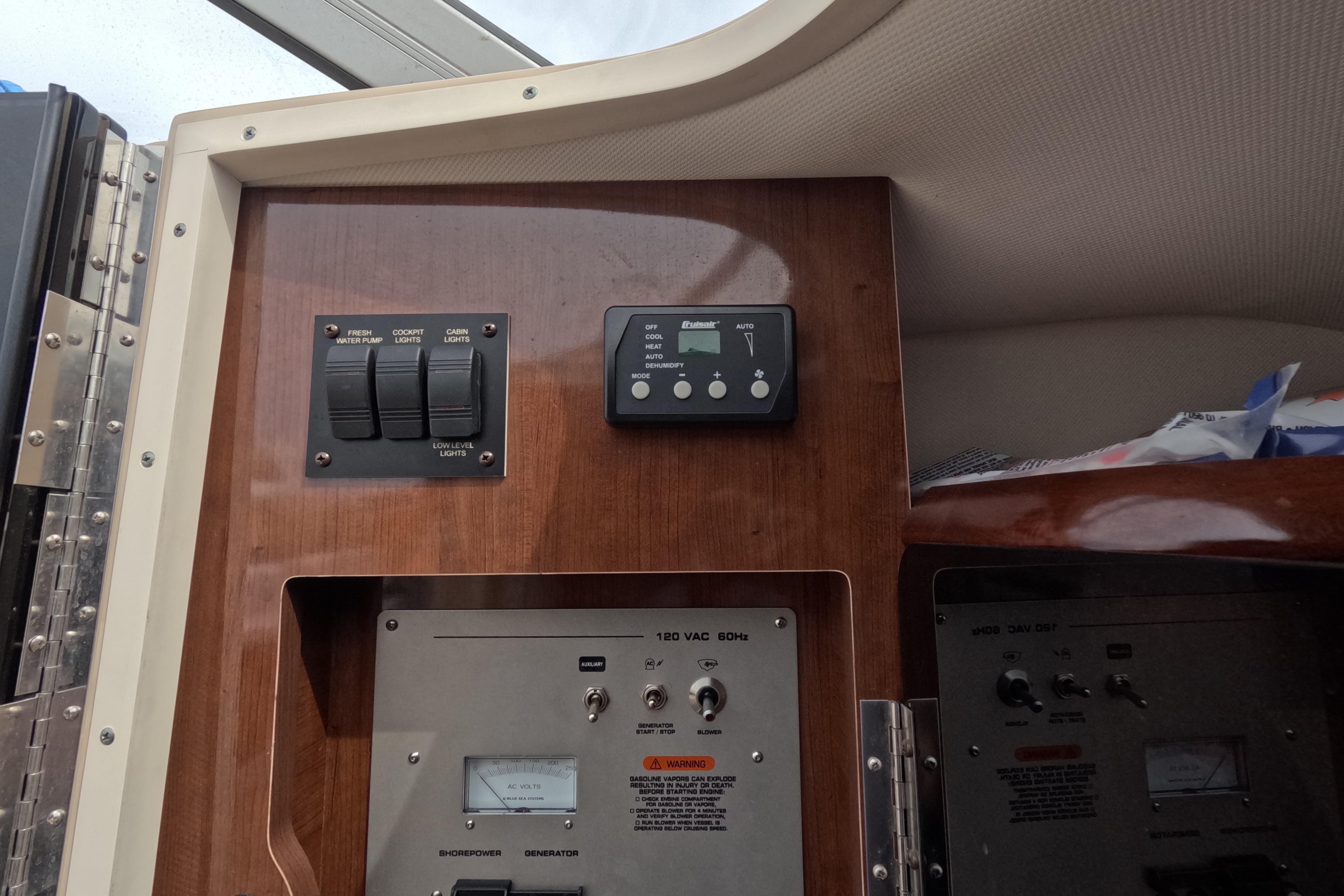 2012 Four Winns V265 control panel with switches and gauges on wooden interior.