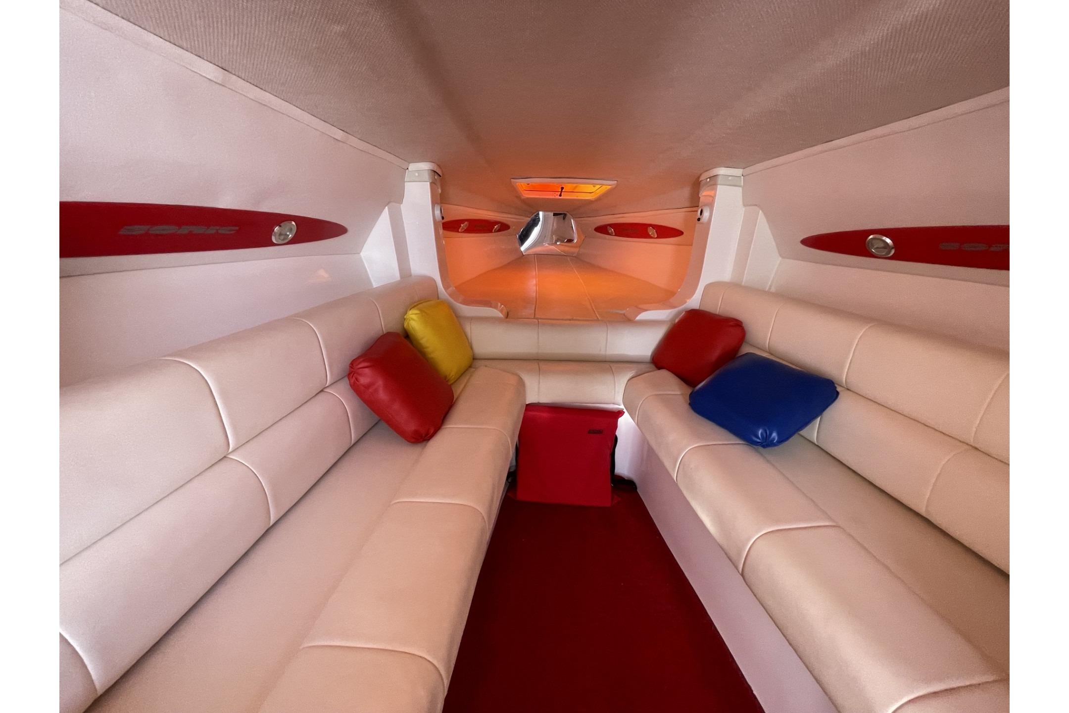 Interior of a 2006 Sonic 386 boat with white seating and colorful cushions.