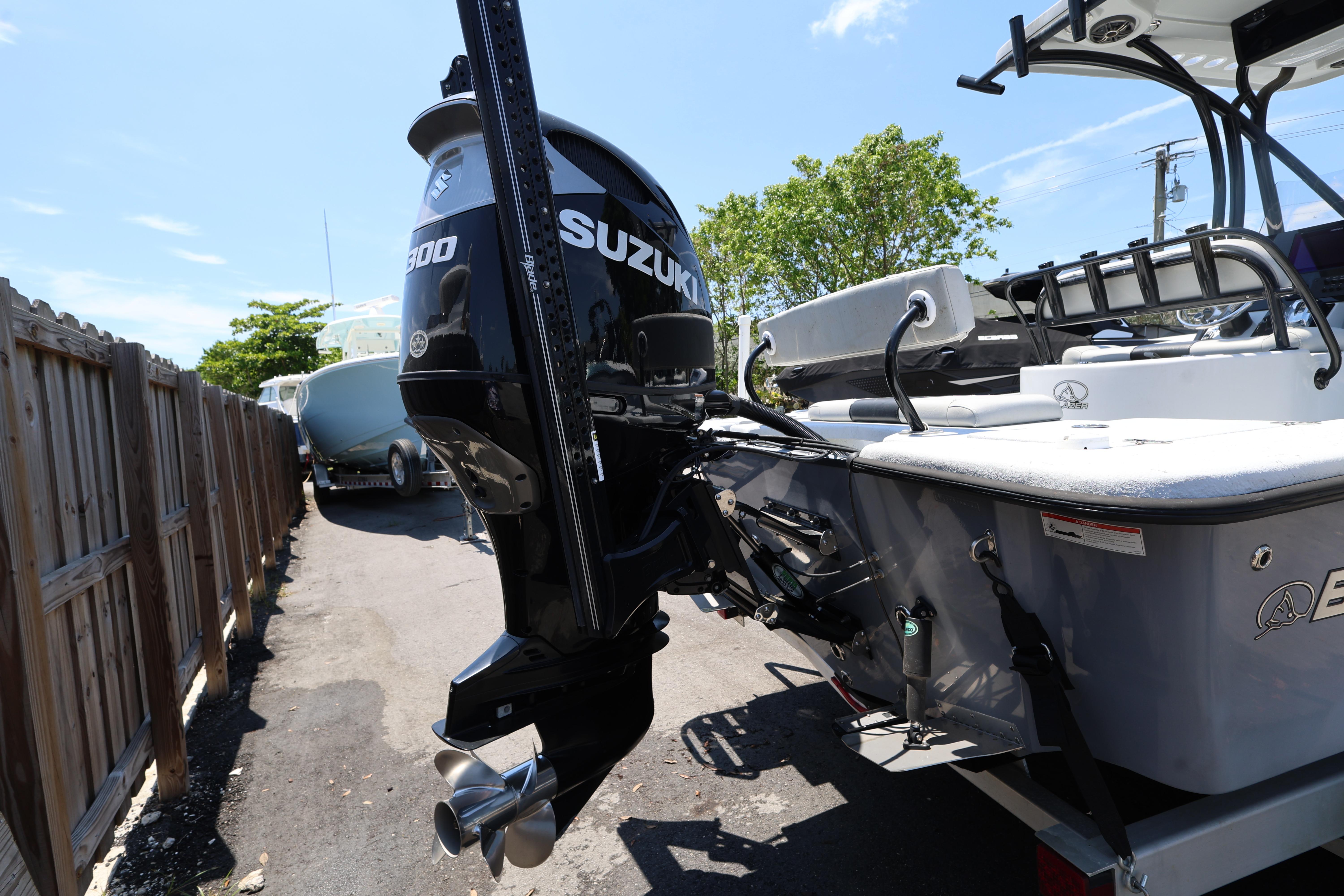 2021 Blazer Bay 2400 boat with Suzuki outboard motor, parked outdoors.