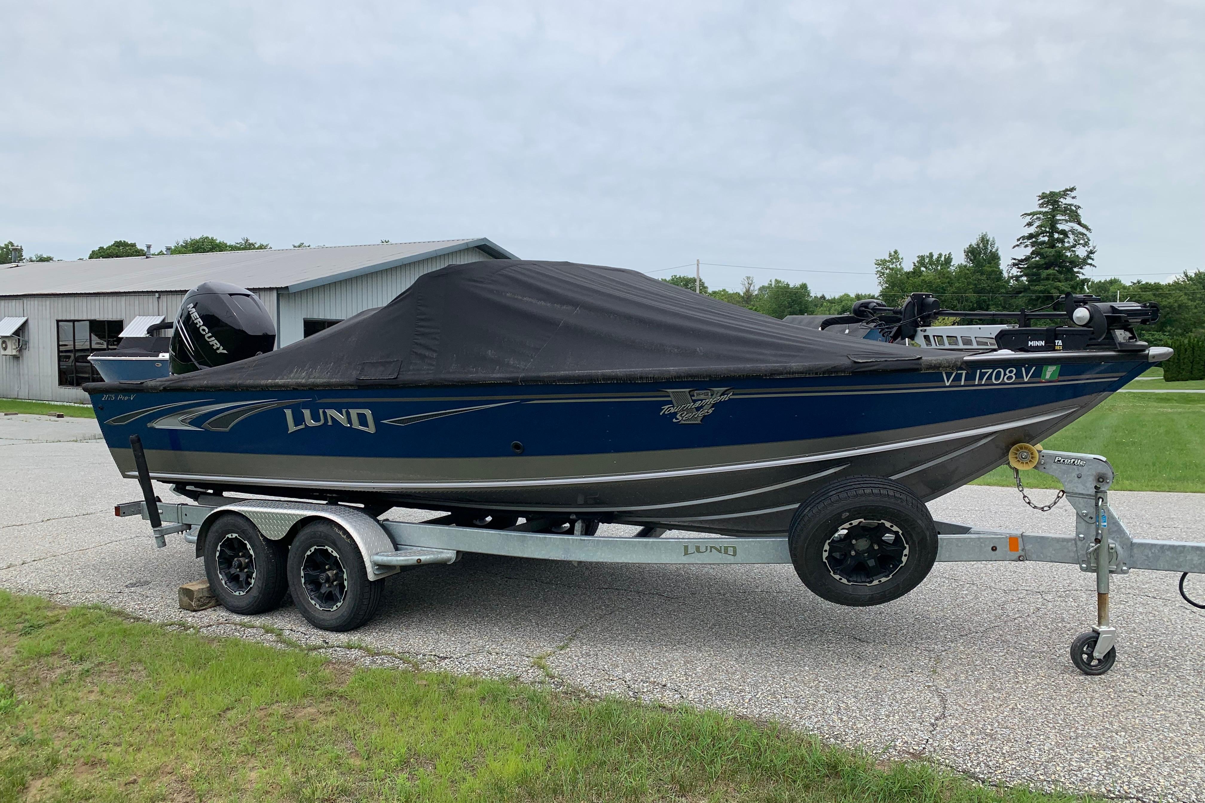 2019 Lund 2175 Pro-V boat on trailer, covered, parked outdoors.