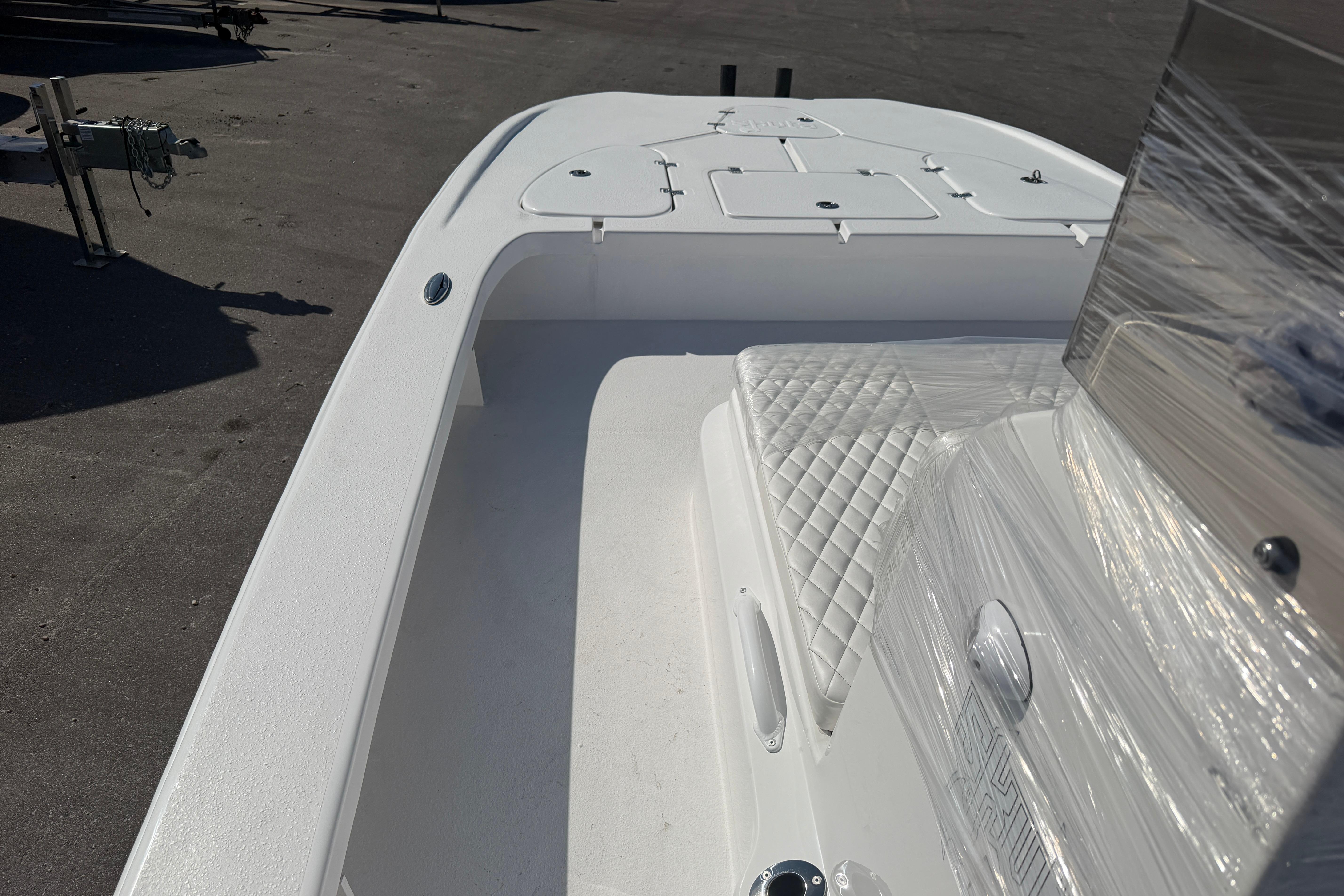 2026 Skuta 24 Cat boat interior with white seating and storage compartments.
