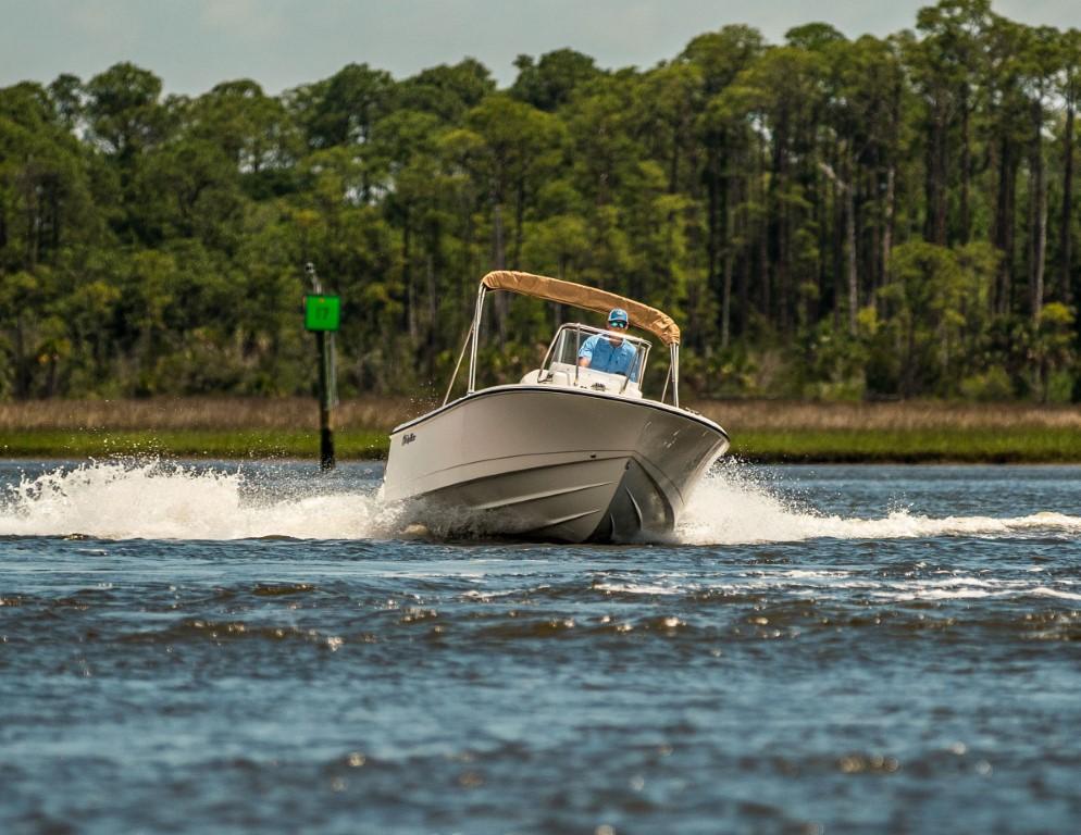 2025 Edgewater 188CC boat cruising on a scenic waterway with lush greenery.