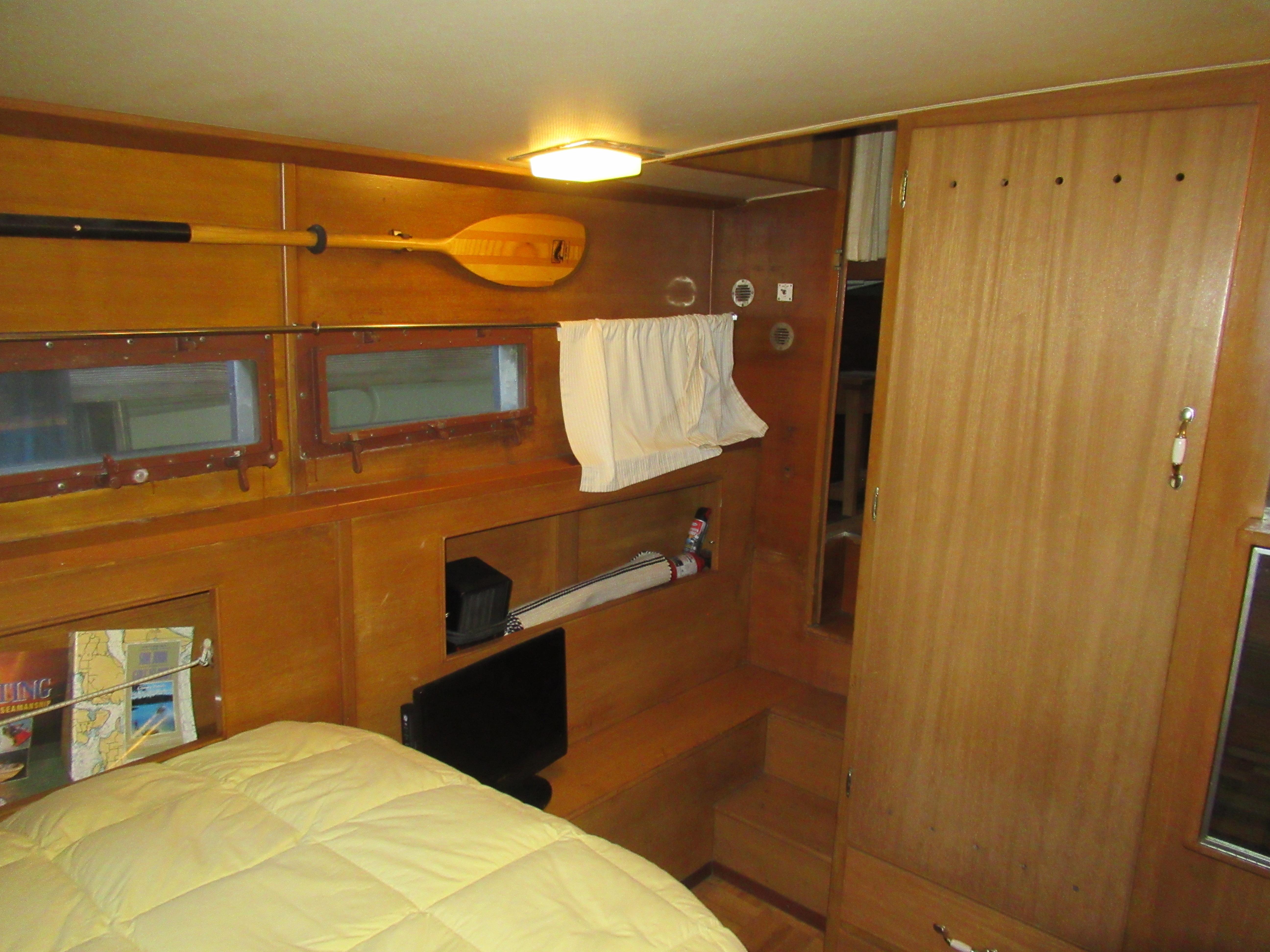1963 Chris-Craft Constellation cabin interior with wood paneling, bed, and nautical decor.