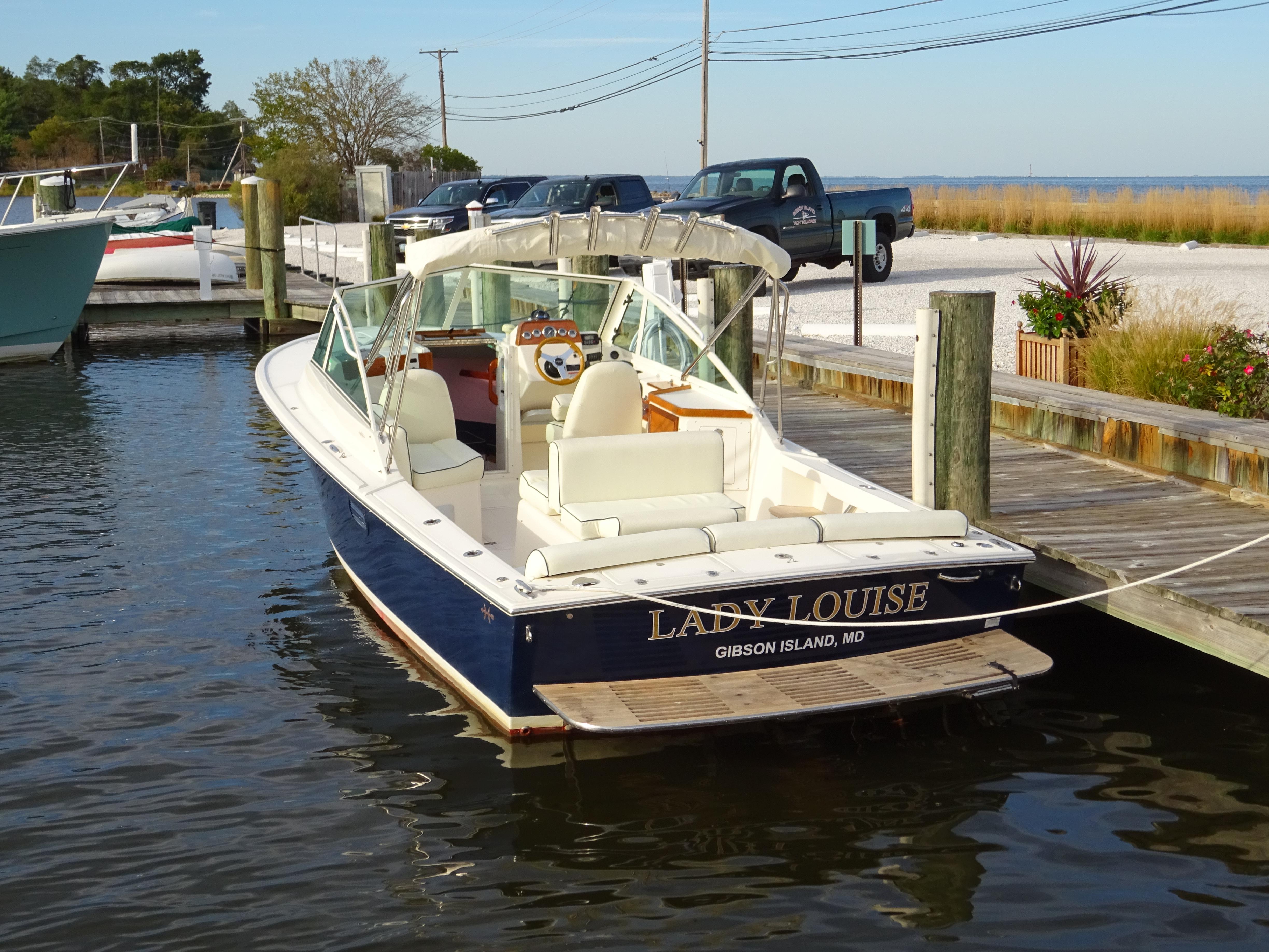 2008 Hunt Yachts Harrier 25 docked, named "Lady Louise," at a marina with scenic background.