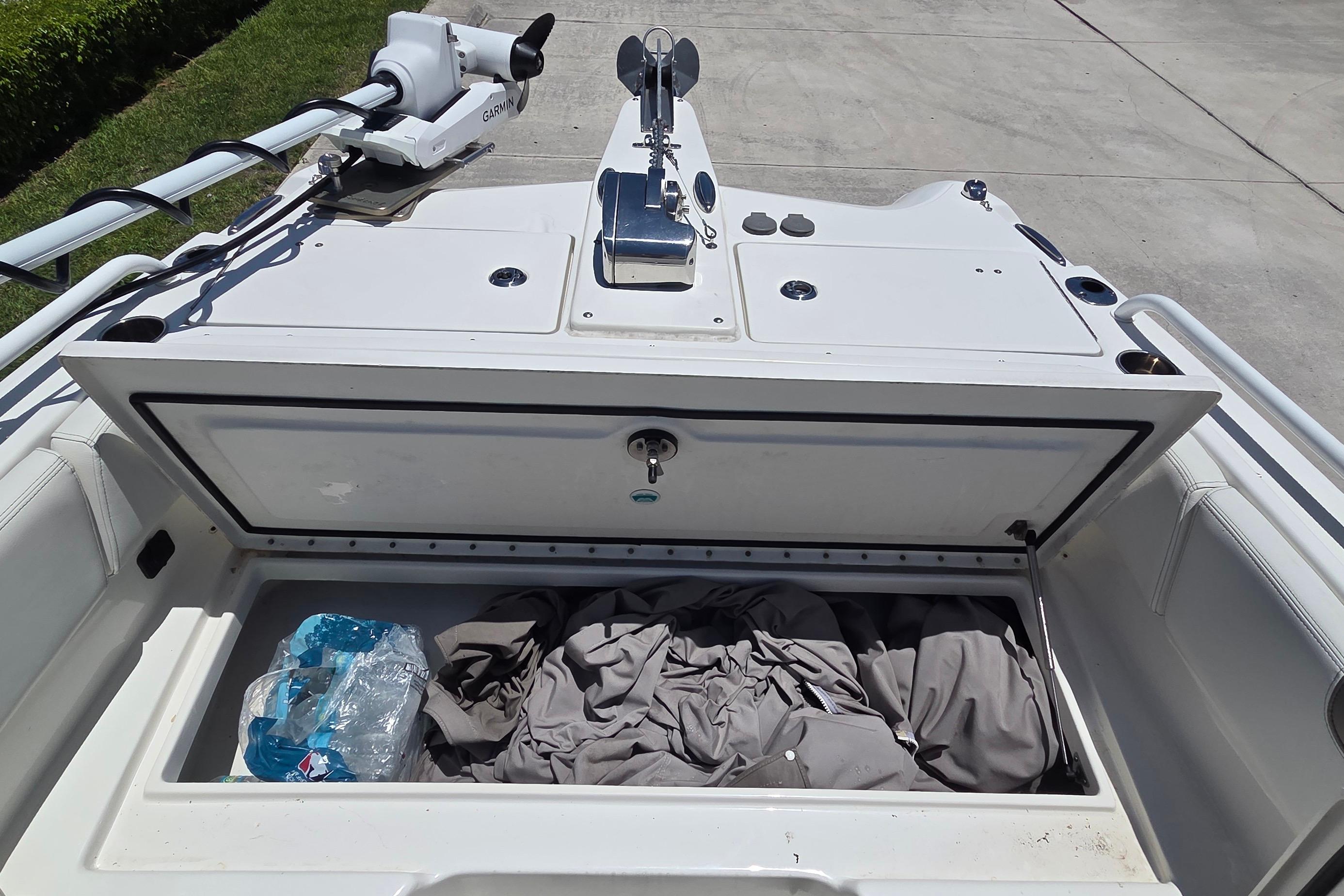 Open storage compartment on 2022 World Cat 255 DC boat with gear and water bottles.