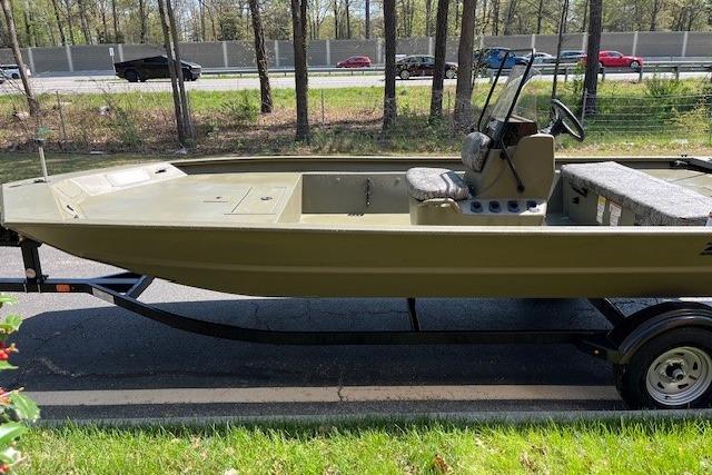 2026 Tracker Grizzly 1860 CC boat on trailer, parked near a road with trees in background.