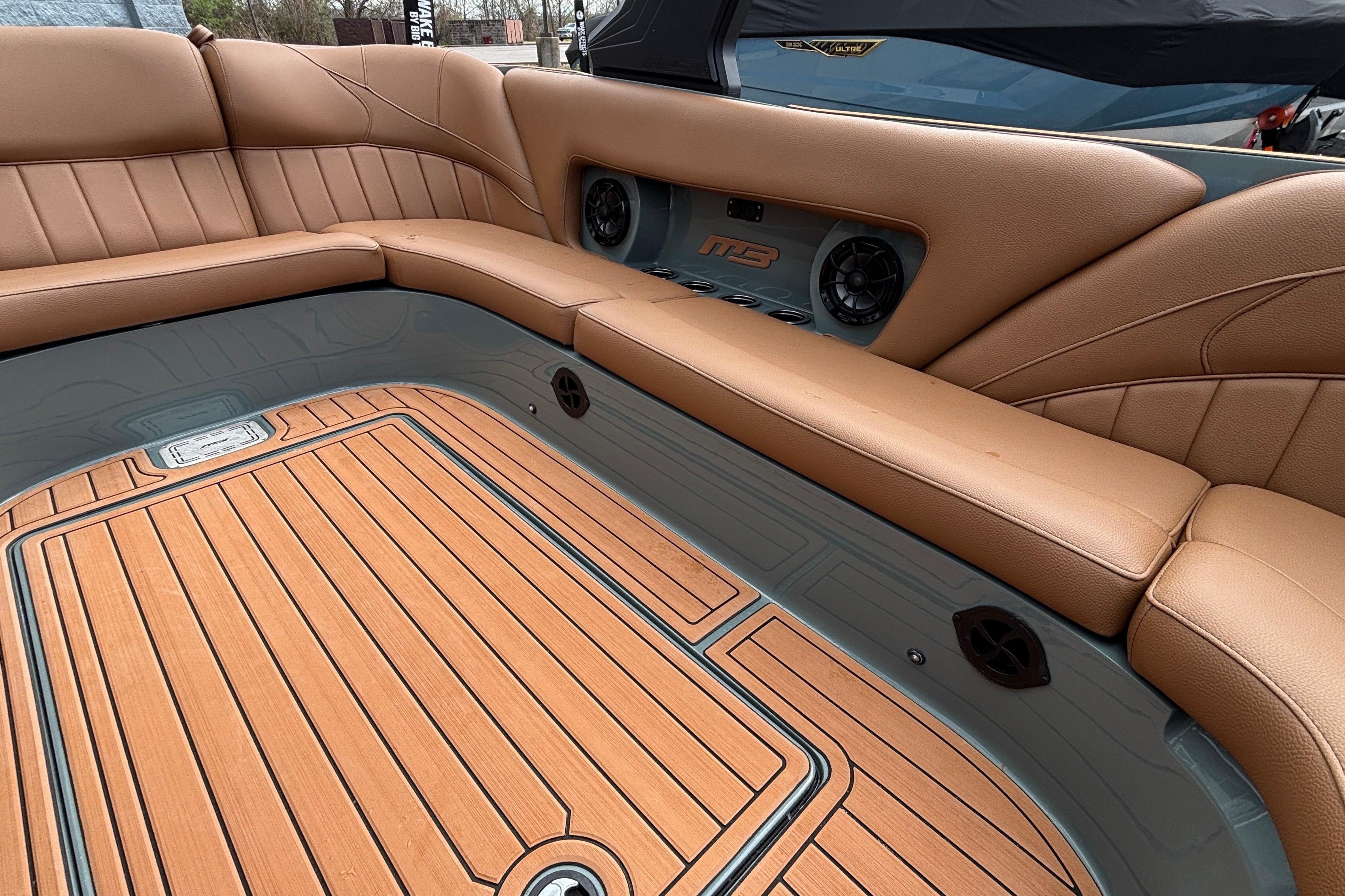 Luxurious interior of 2026 MB B52 23 Classic boat with tan seating and wood flooring.