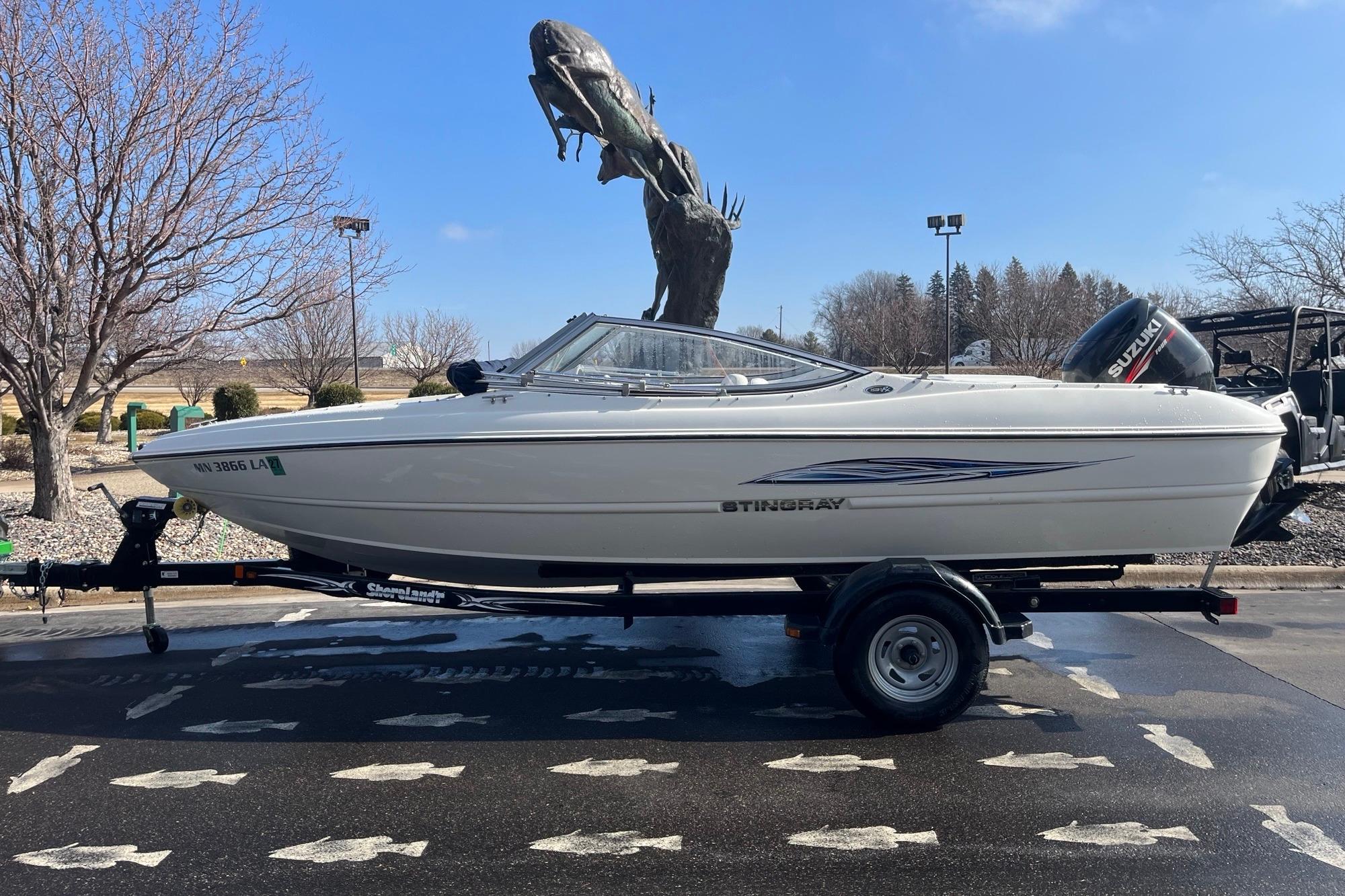 2013 Stingray 191 RX boat on trailer, parked outdoors with a large fish statue in the background.