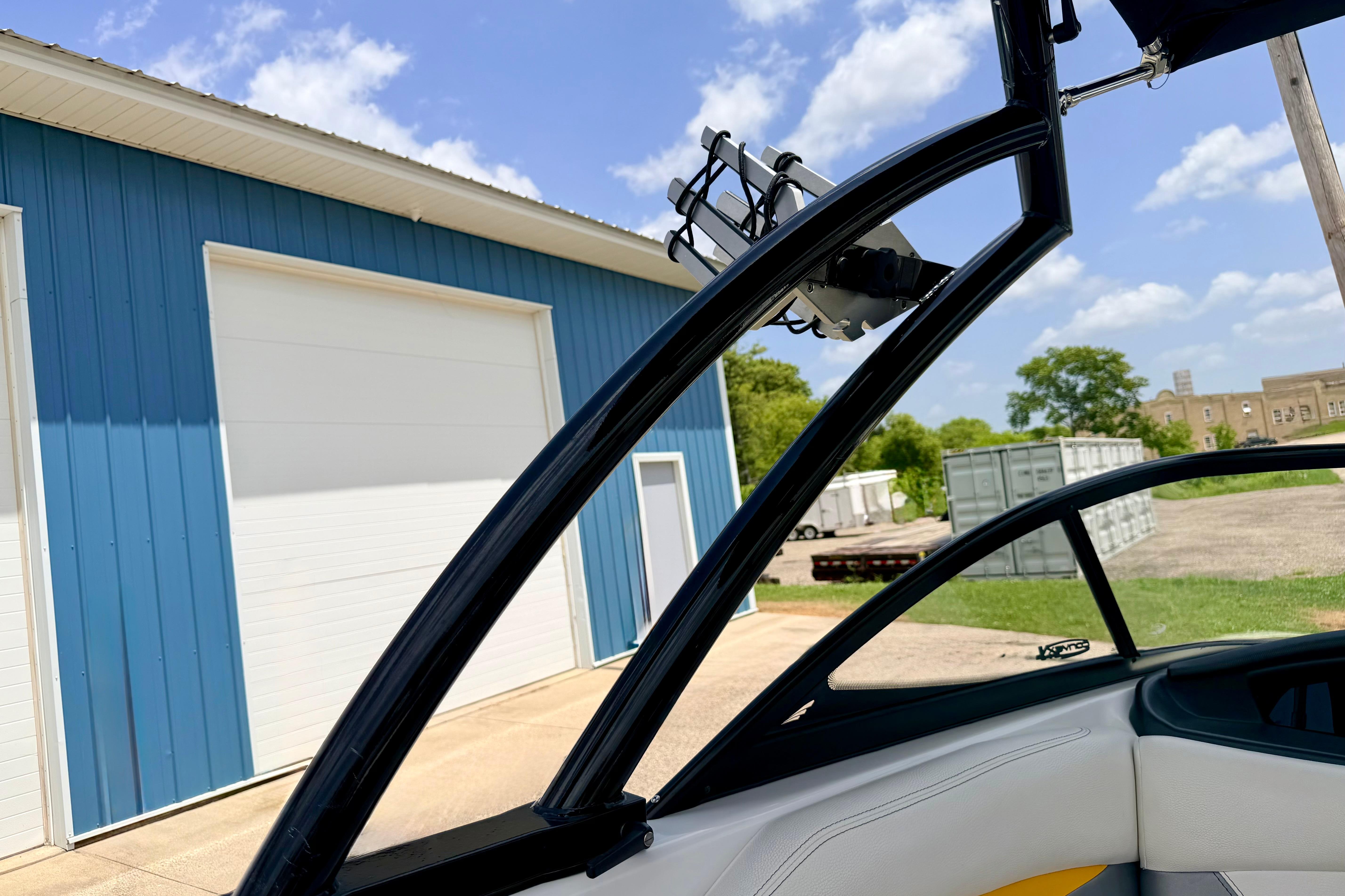 2014 Tigé R20 boat near blue warehouse under clear sky.