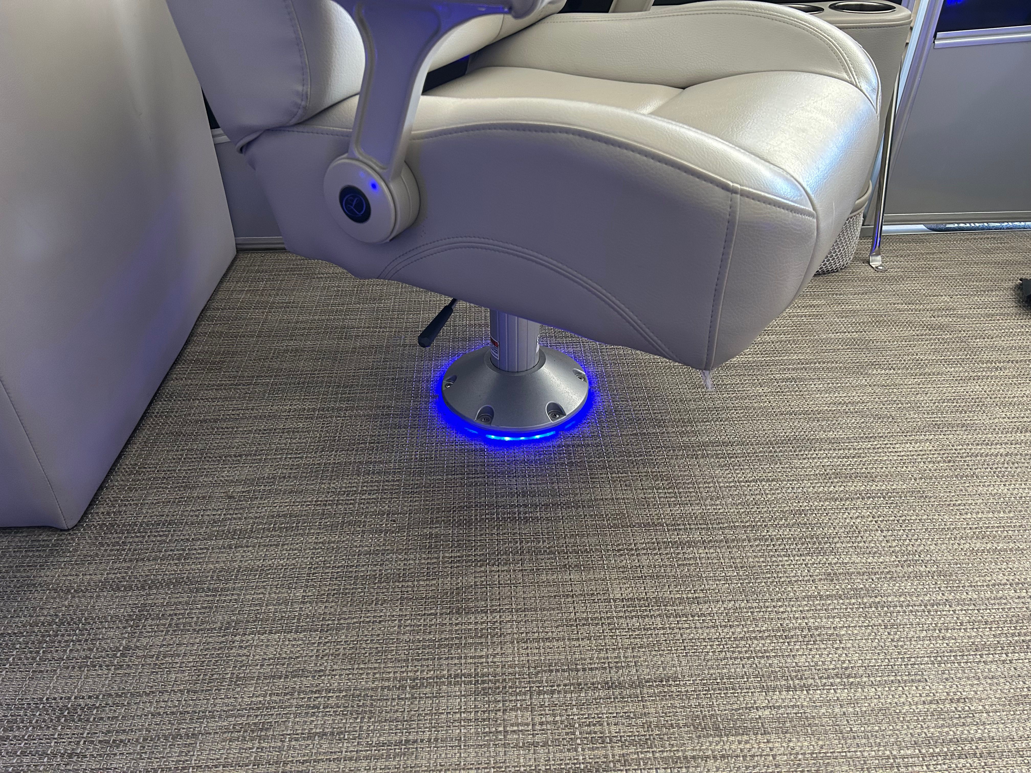 A boat seat with blue LED lighting at the base on a carpeted floor.