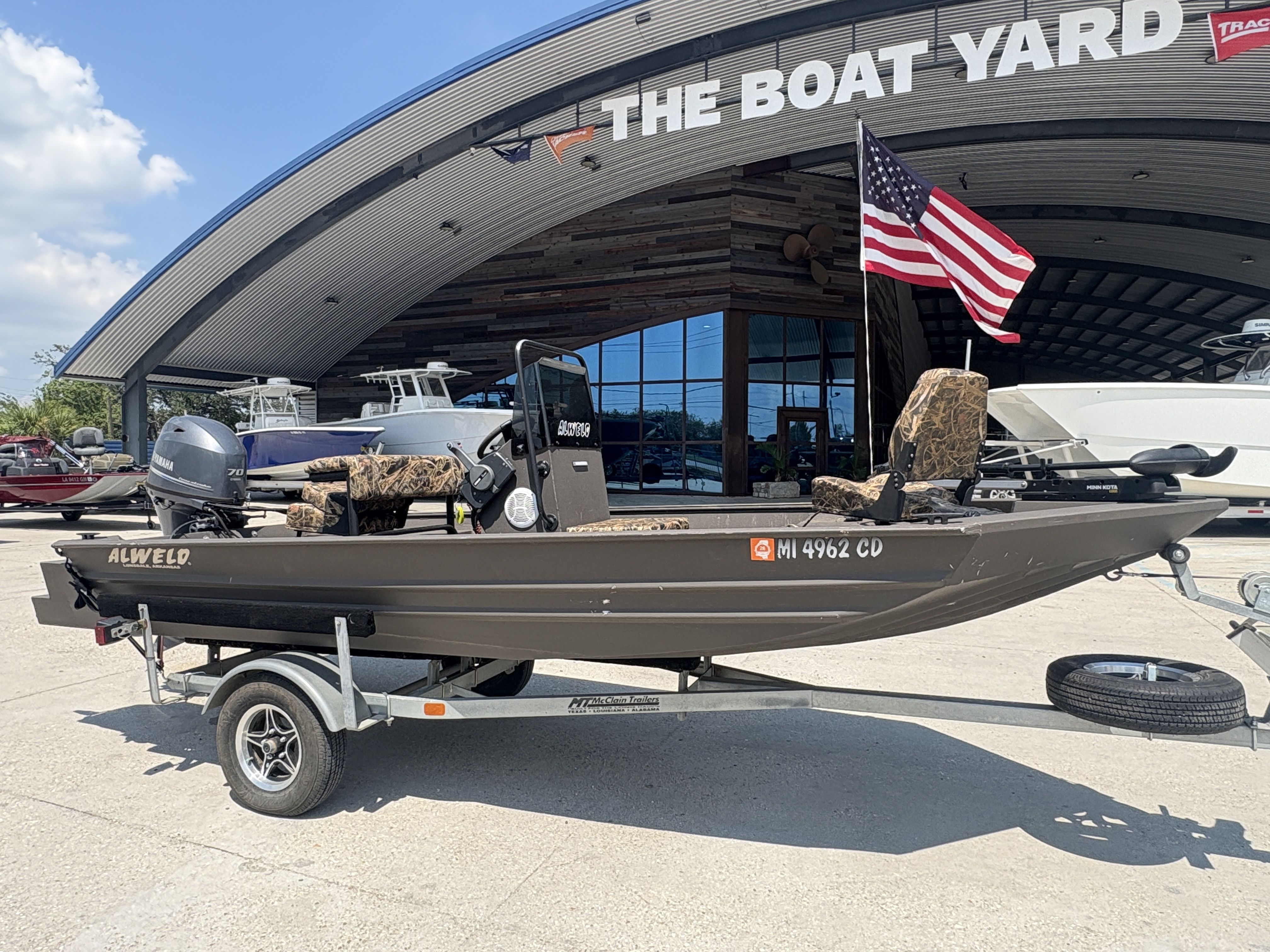 2023 Alweld 16x52 Marsh boat on trailer at dealership, American flag displayed.