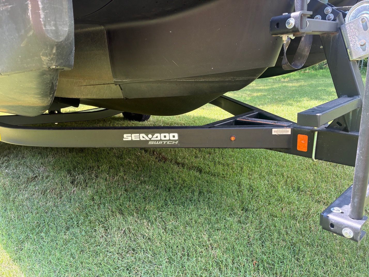 A 2023 Sea-Doo Switch Sport 18 on a trailer on grass.
