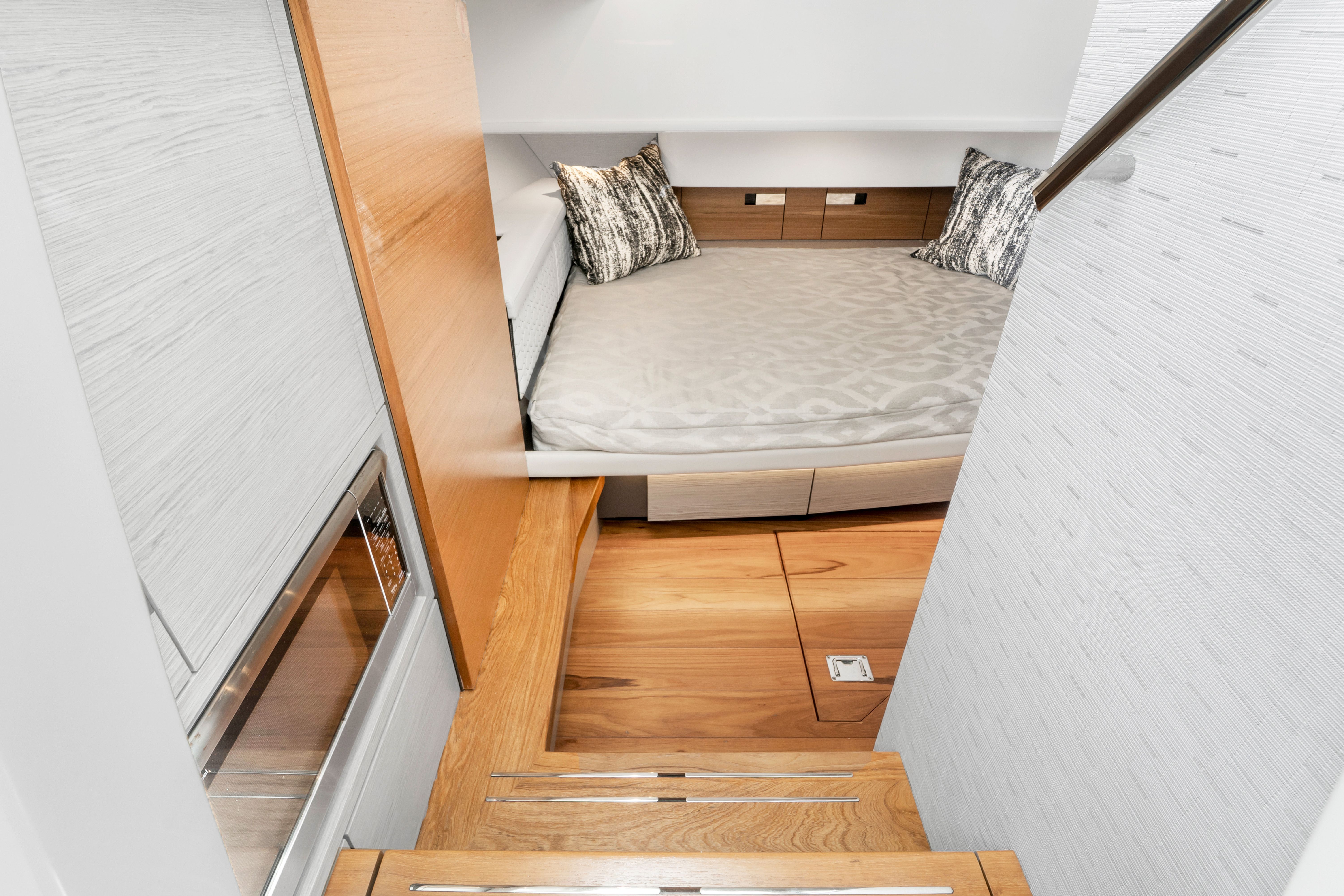 Interior of a 2023 Tiara Yachts 38 LS with a cozy bed and wooden steps.