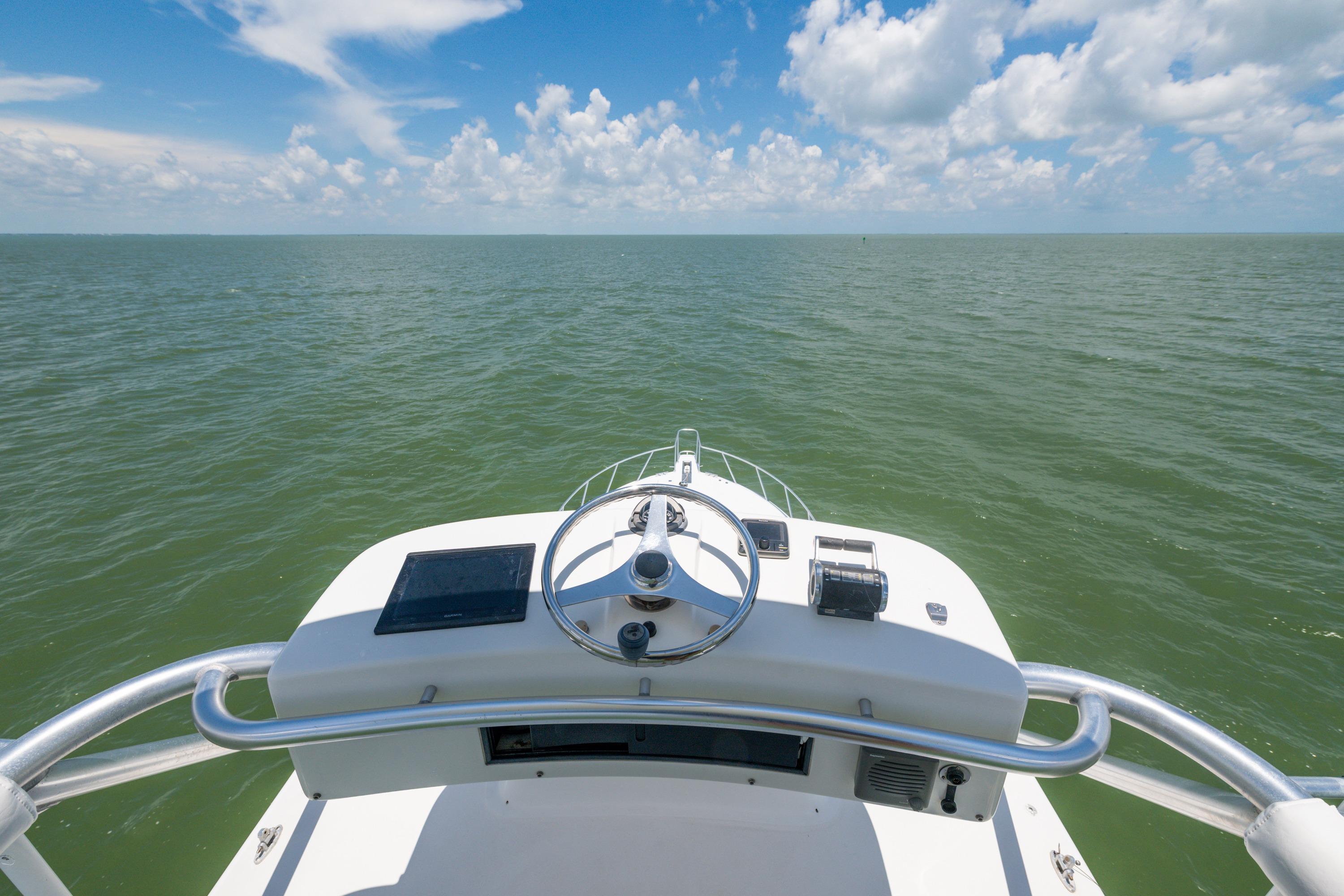Helm view of 2010 Cabo 45 Express boat on open sea under blue sky.