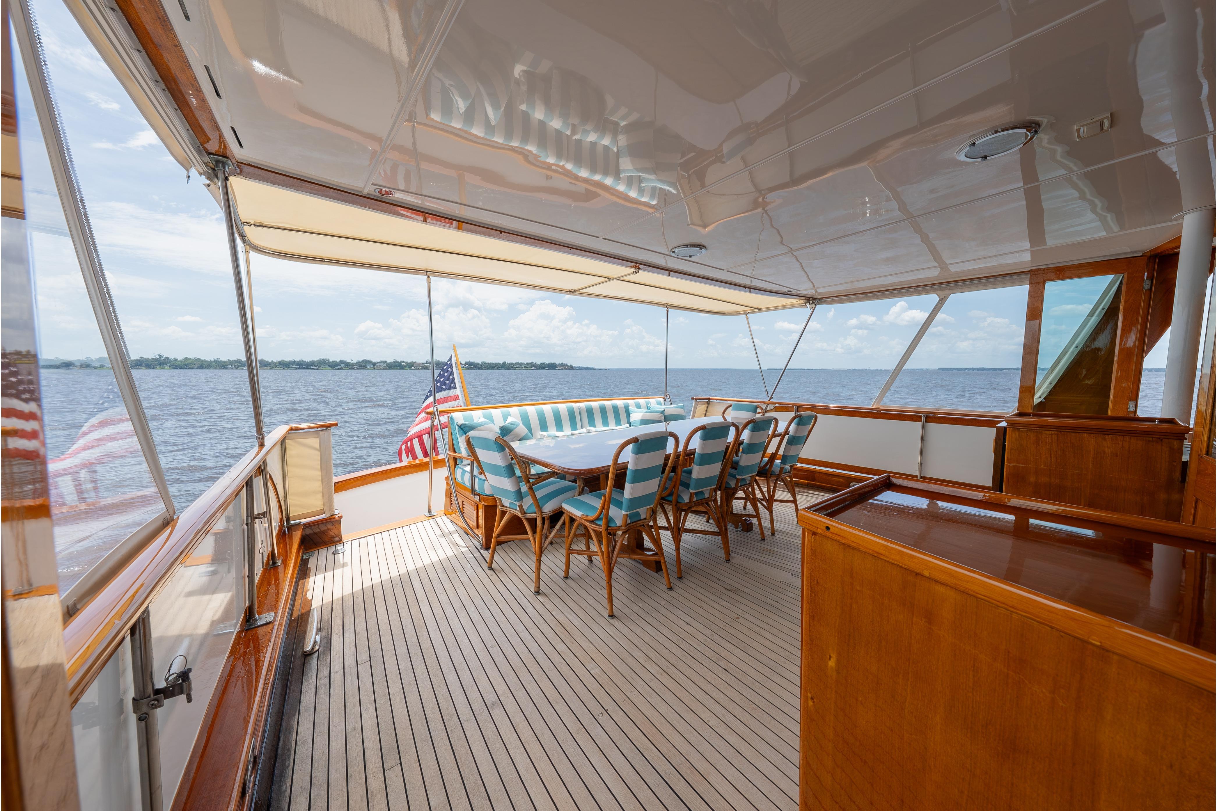 Luxurious 1963 Trumpy Classic yacht deck with dining area, overlooking serene waters.