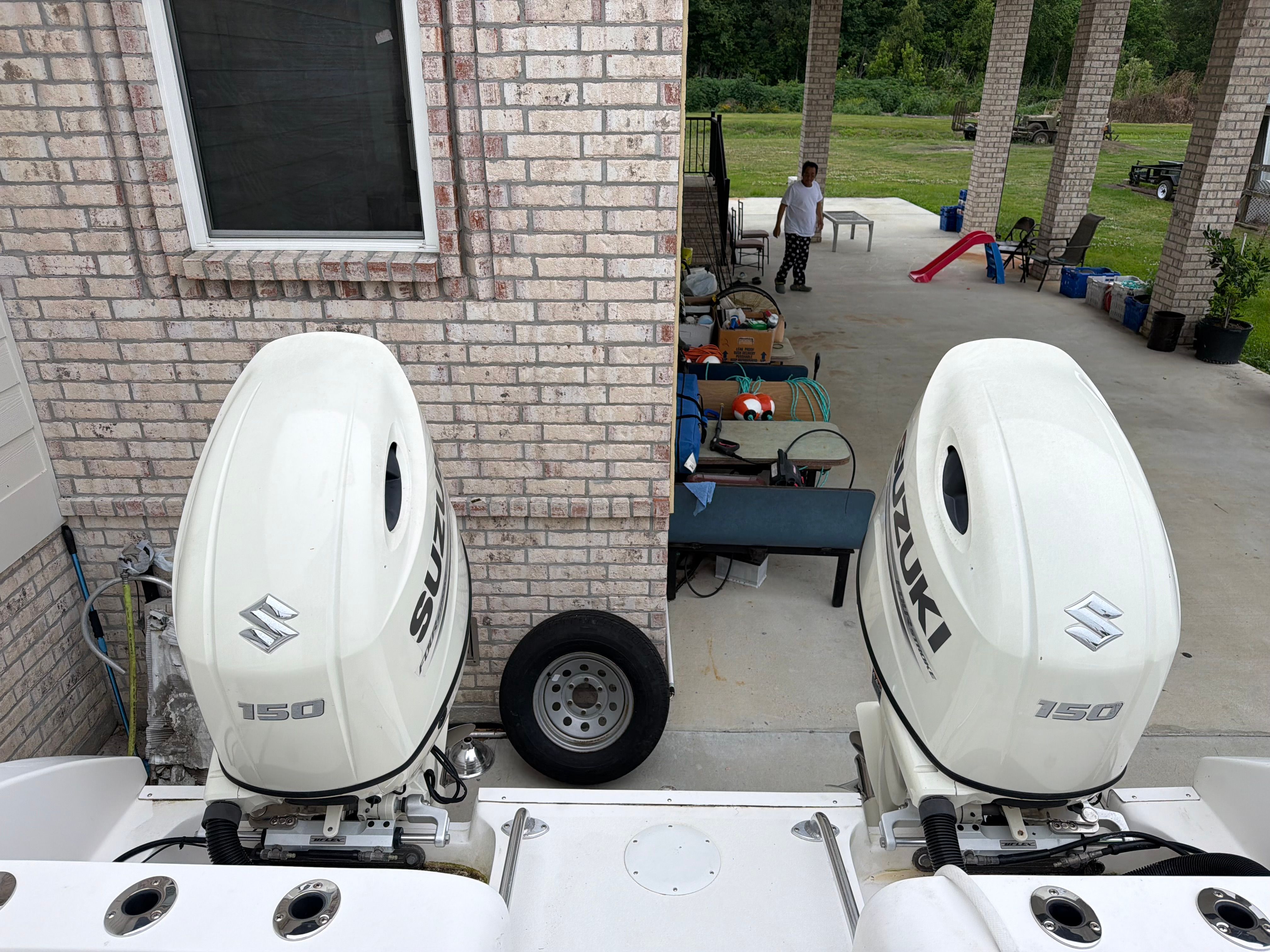 Two Suzuki outboard motors on a boat docked at a pier.