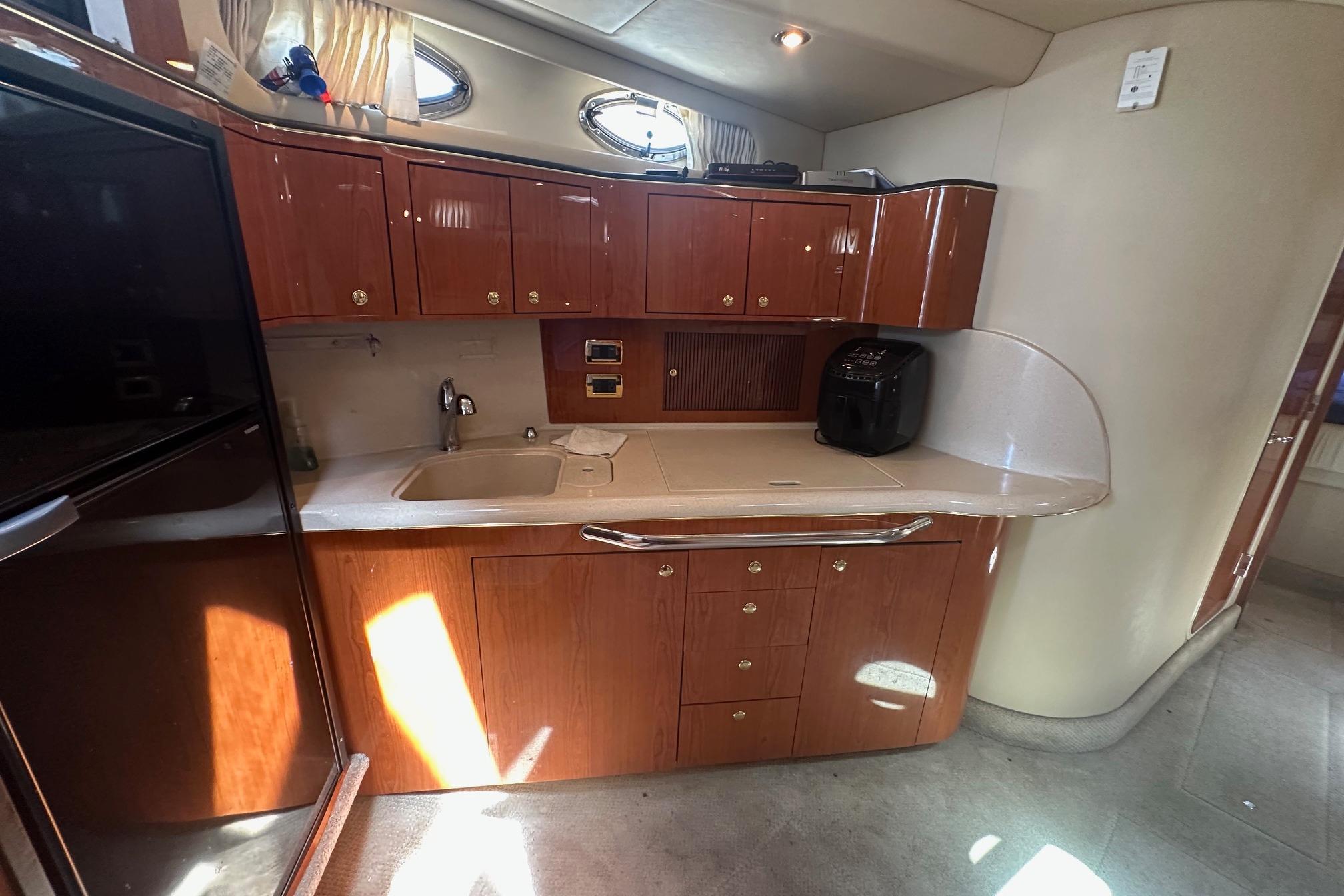 Luxurious 2001 Sea Ray 410 Sundancer yacht kitchen with wood cabinetry and modern appliances.