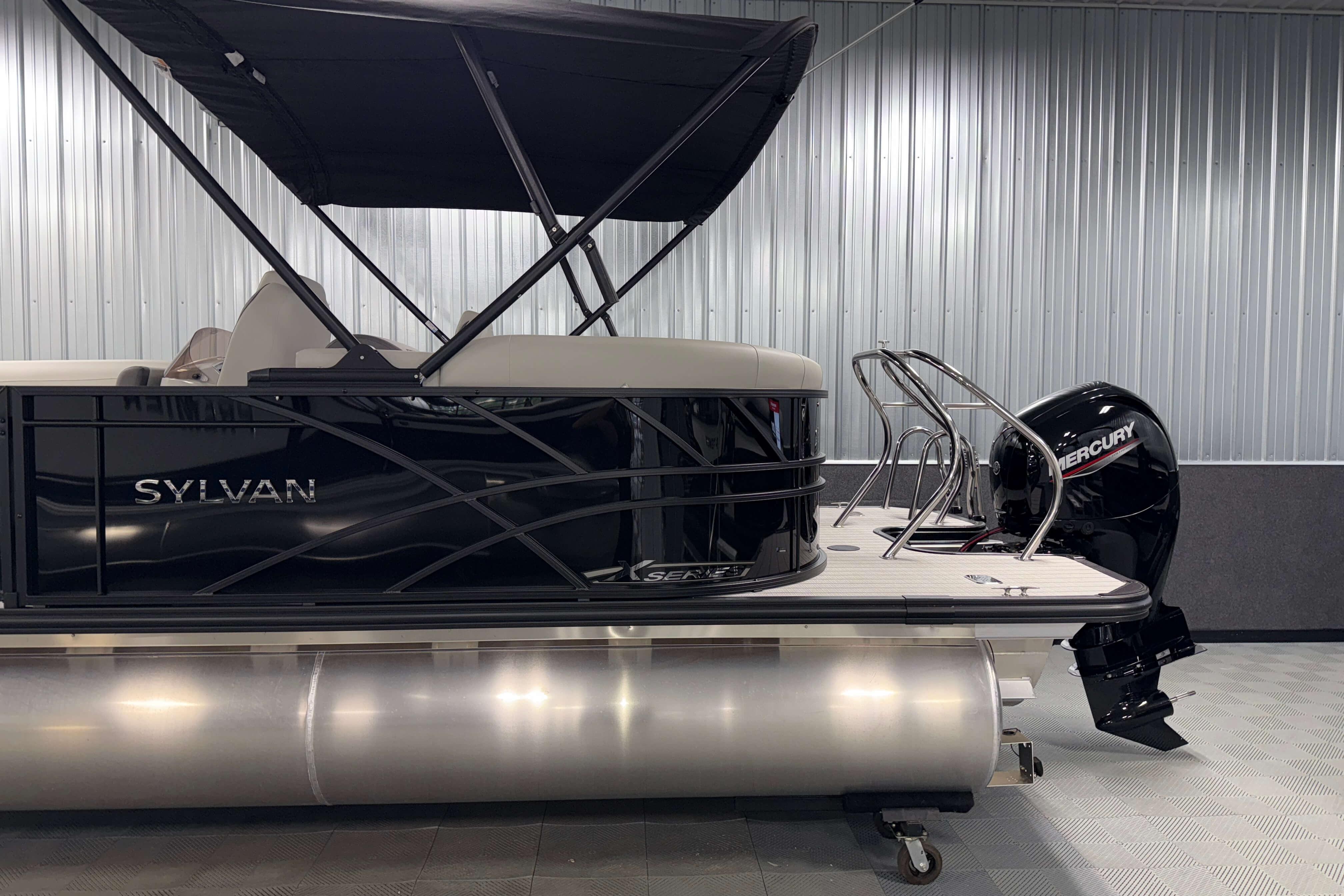 2026 Sylvan Mirage X1 pontoon boat with Mercury outboard motor in showroom.