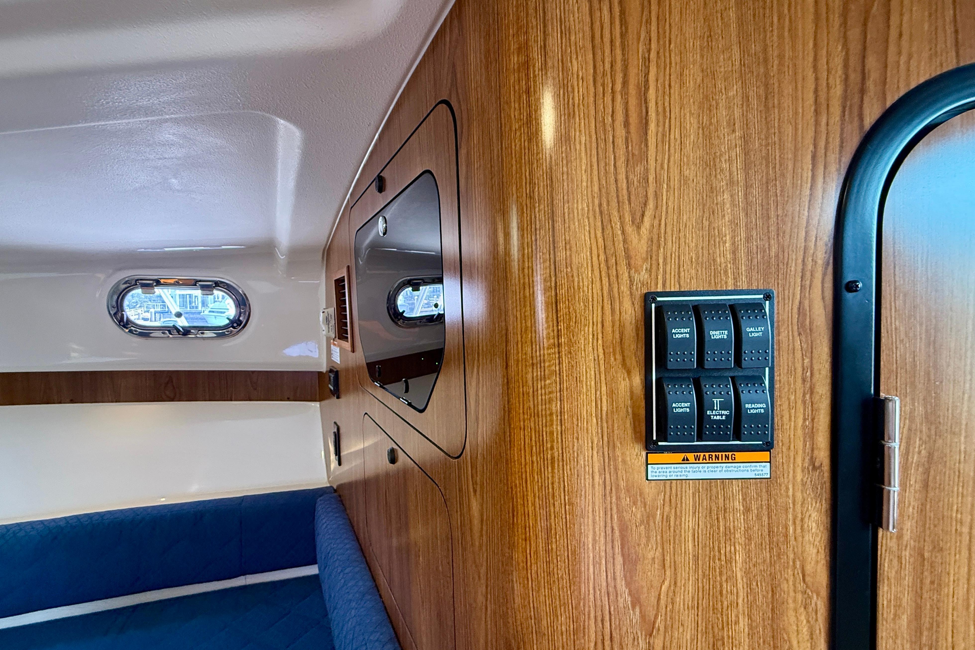 Interior of 2012 Pursuit OS 345 Offshore boat with wood paneling and control switches.