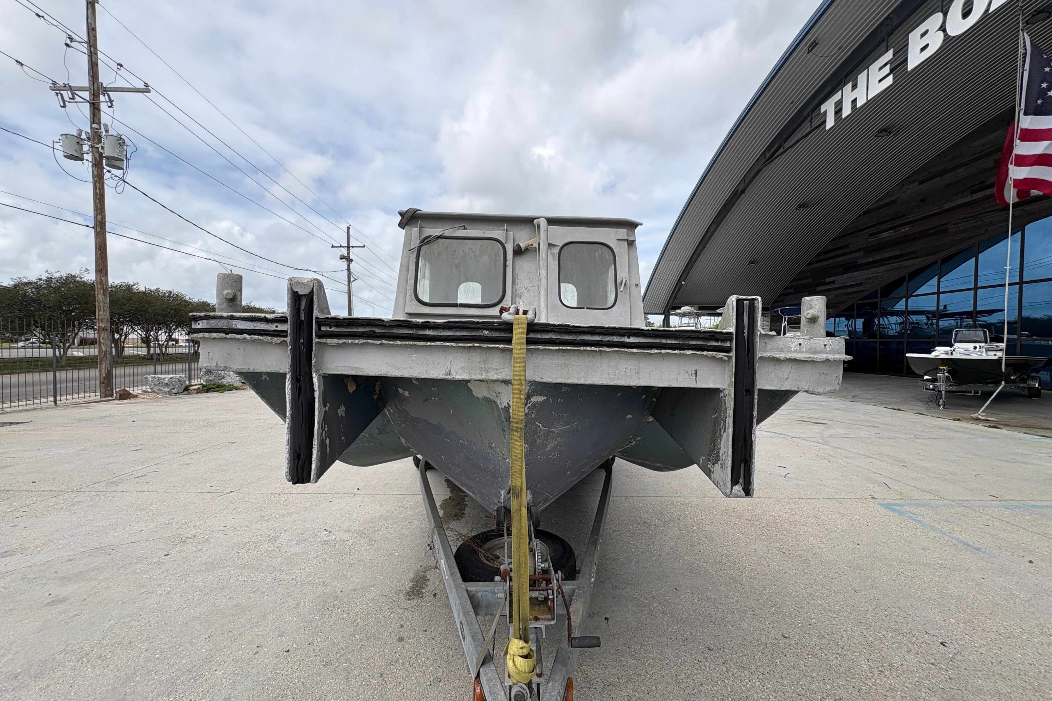 Front view of a 1972 custom 23' work/push boat on a trailer, outside a building.