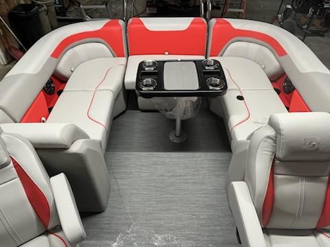 2025 Sweetwater 2286SB boat interior with red and white seating and central table.