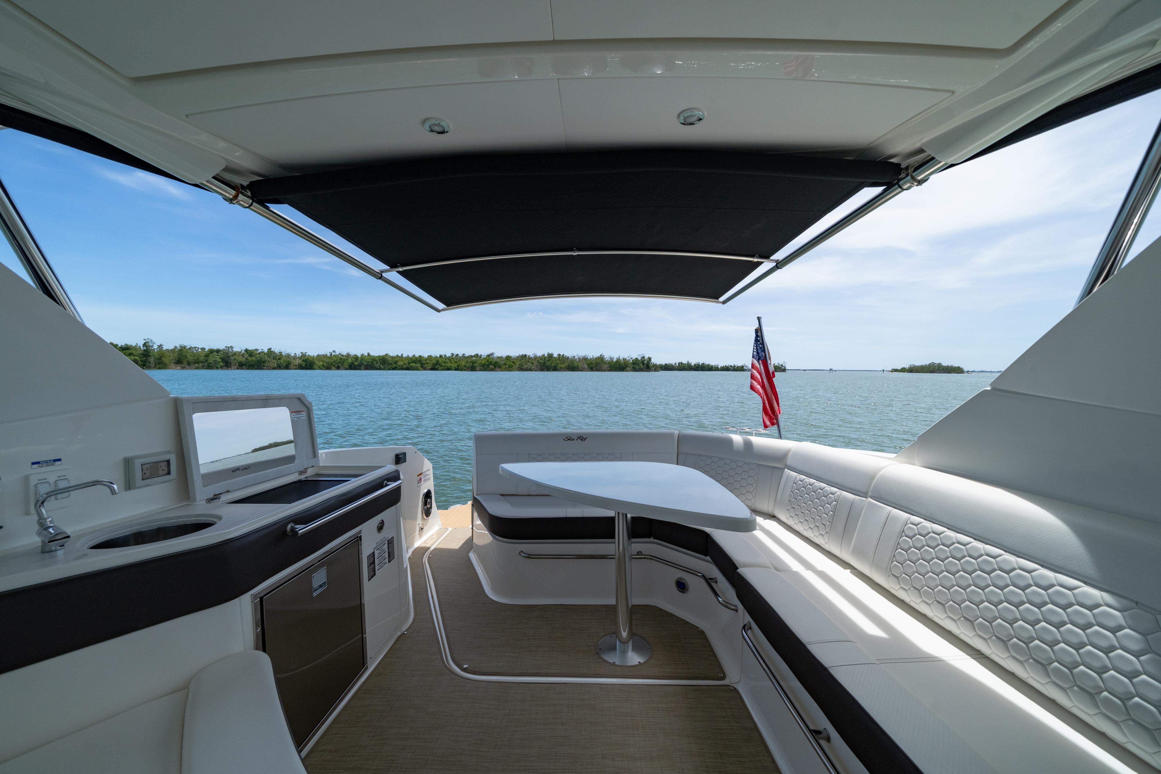 2024 Sea Ray Sundancer 320 Outboard interior with seating, table, and water view.
