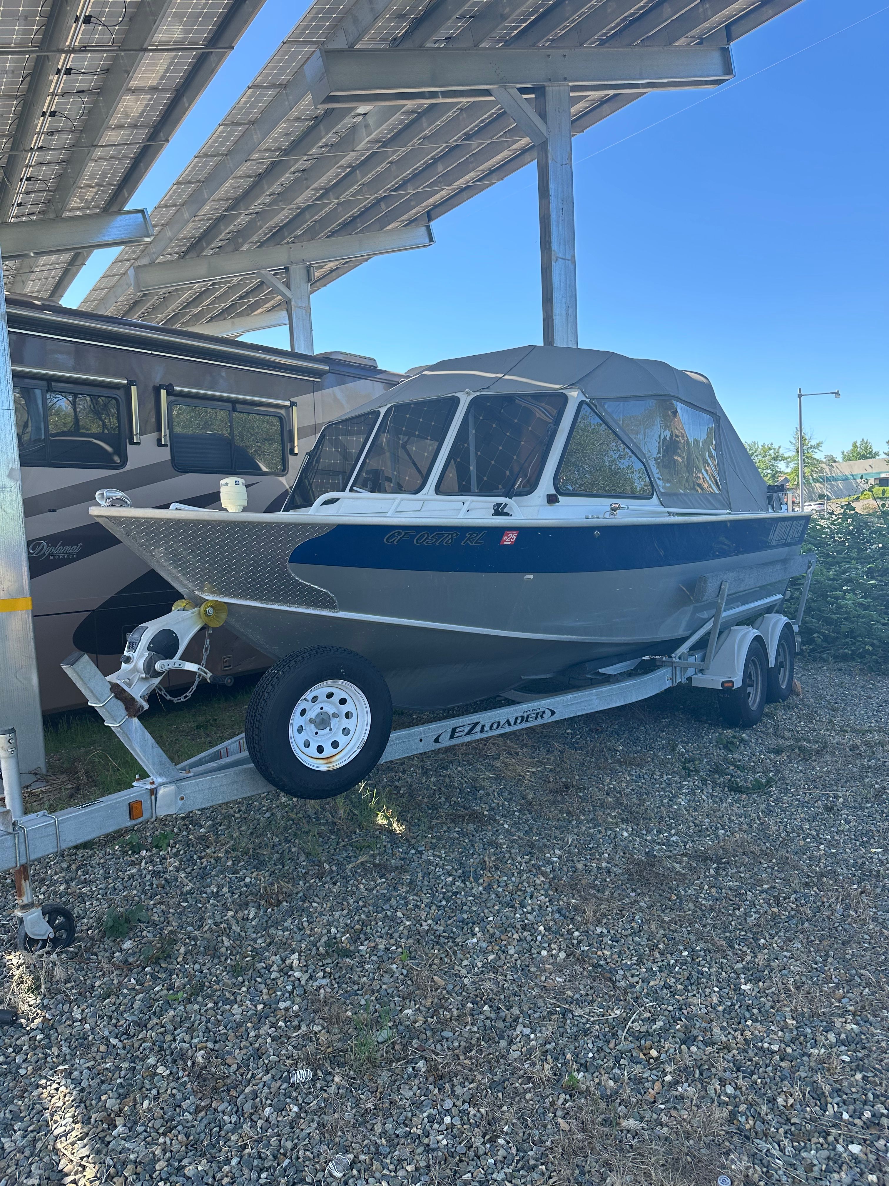 A 2006 North River aluminum boat on a trailer under a carport.