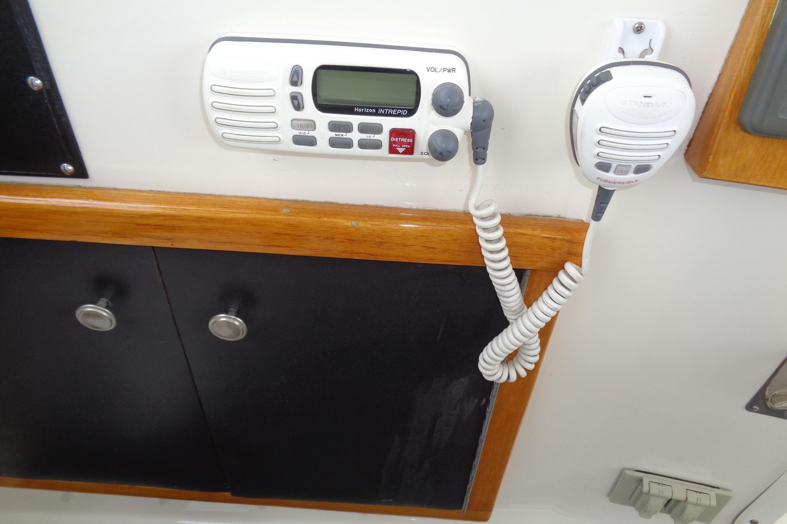VHF radio system on 1981 Hatteras 48 Cockpit Motor Yacht, featuring wood trim and storage cabinets.