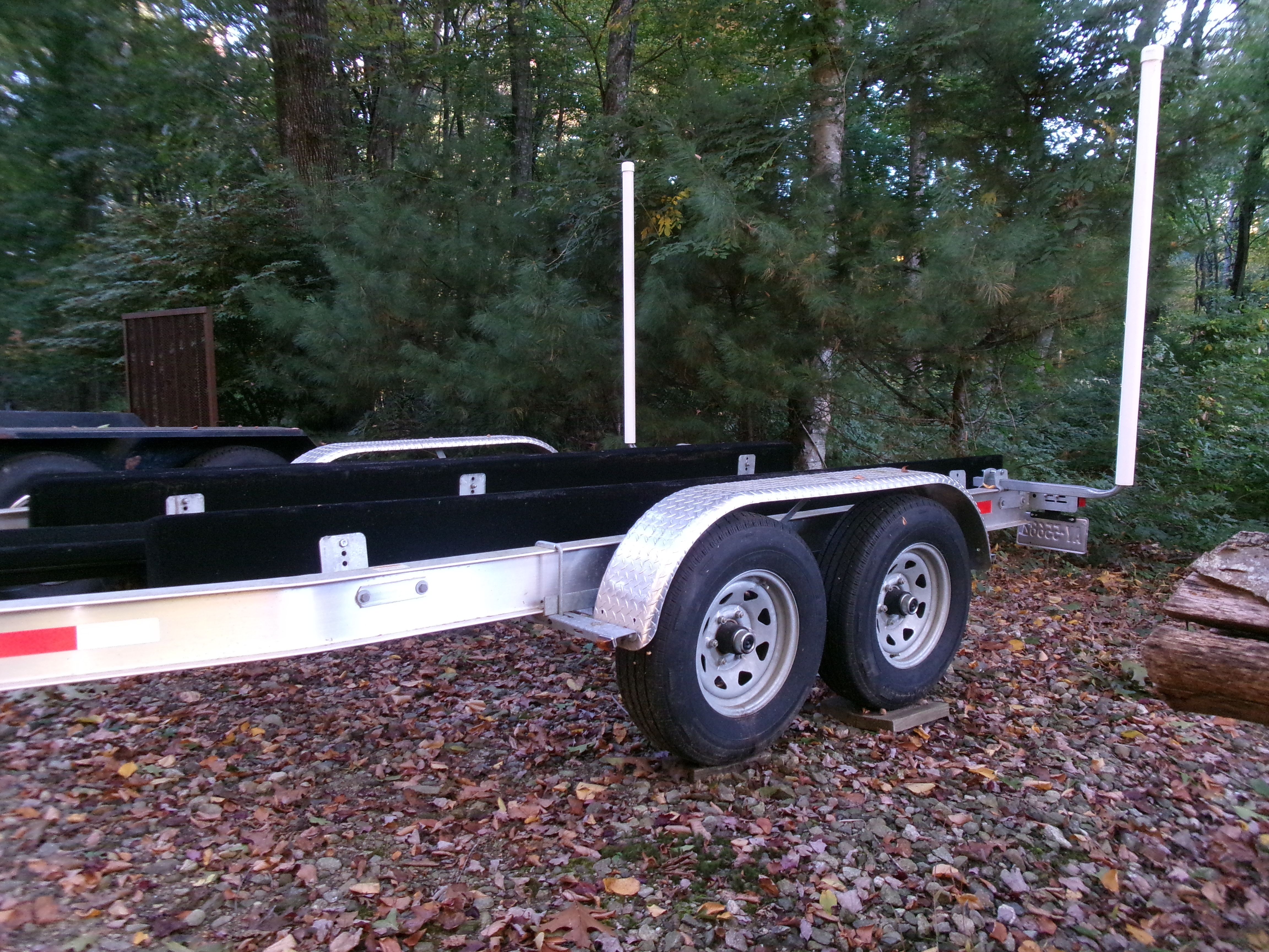 Boat trailer in a wooded area with autumn leaves.