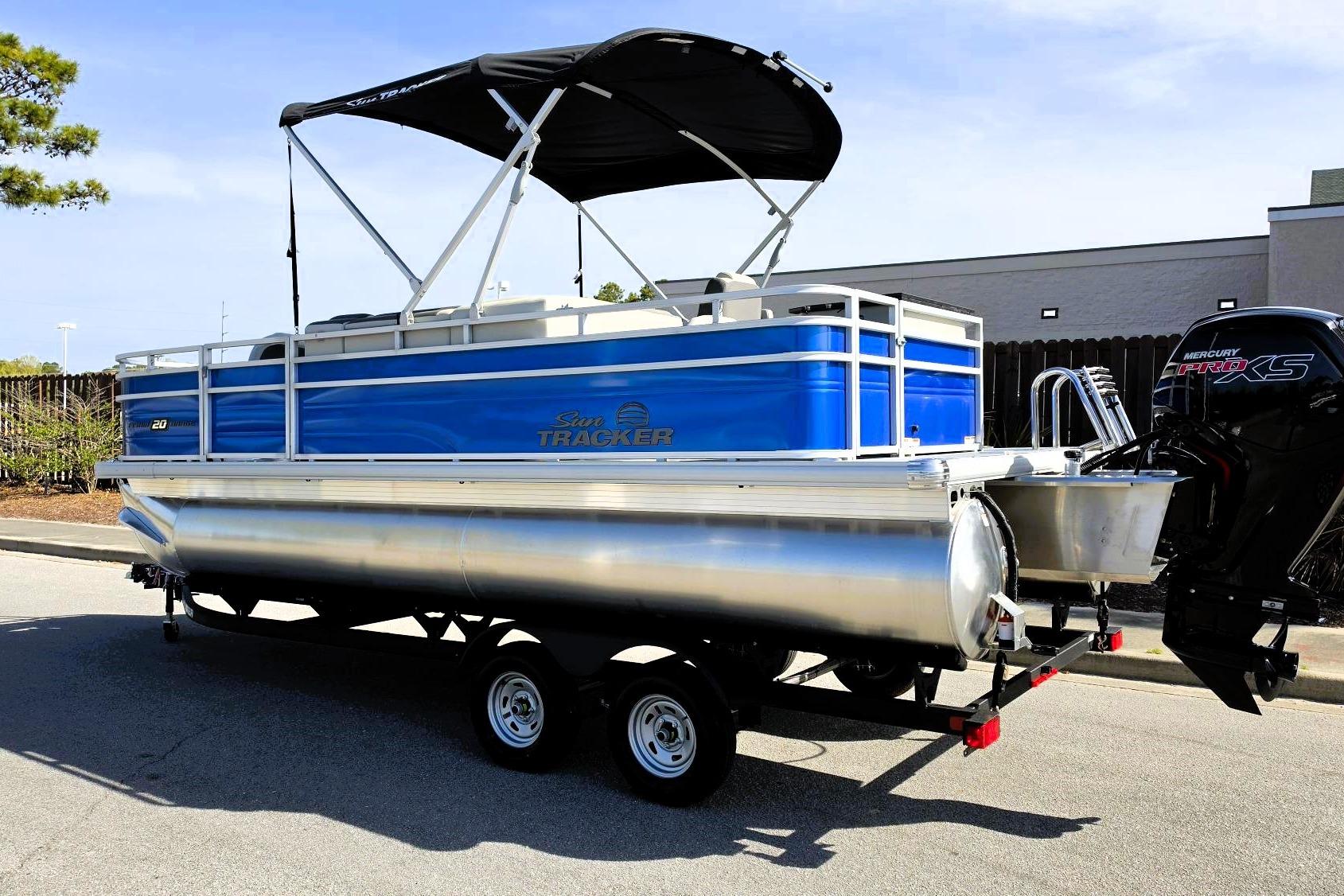 2026 Sun Tracker Fishin' Barge 20 DLX pontoon boat with canopy and outboard motor.