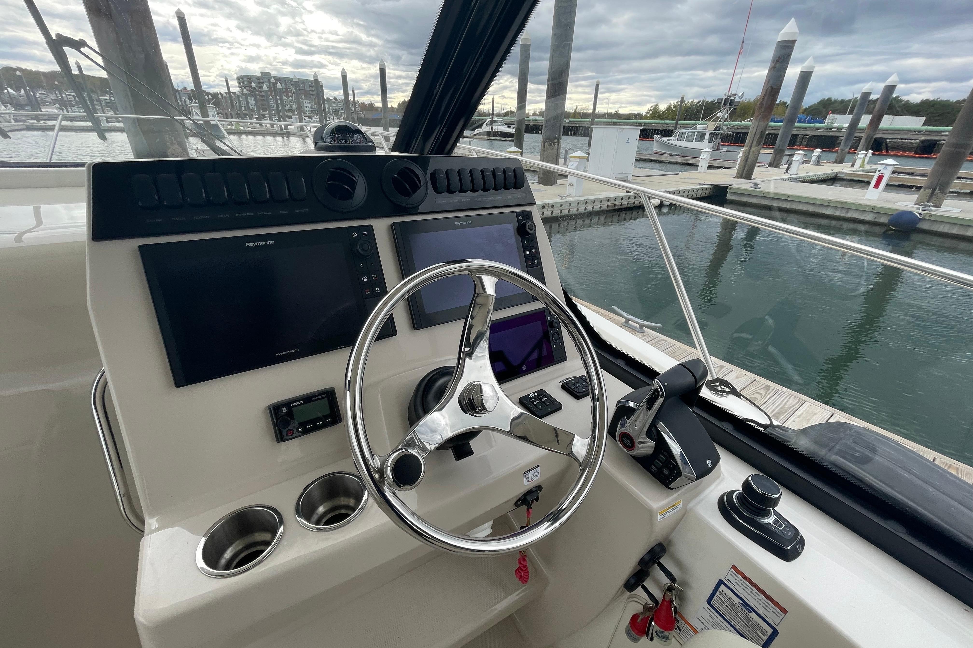 2023 Boston Whaler 325 Conquest helm with dual screens and steering wheel at marina.