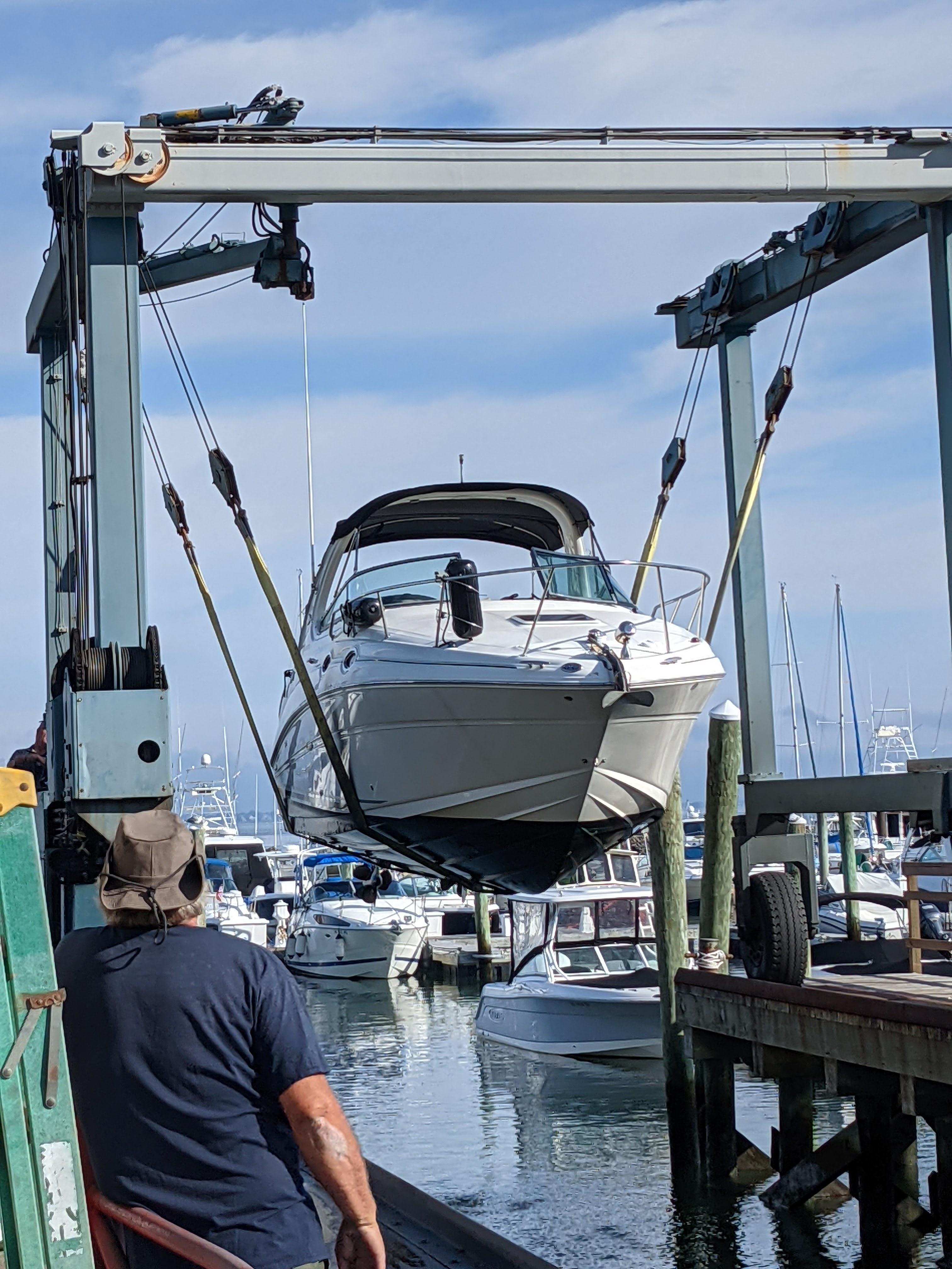 2005 Sea Ray 280 Sundancer being lifted at a marina.