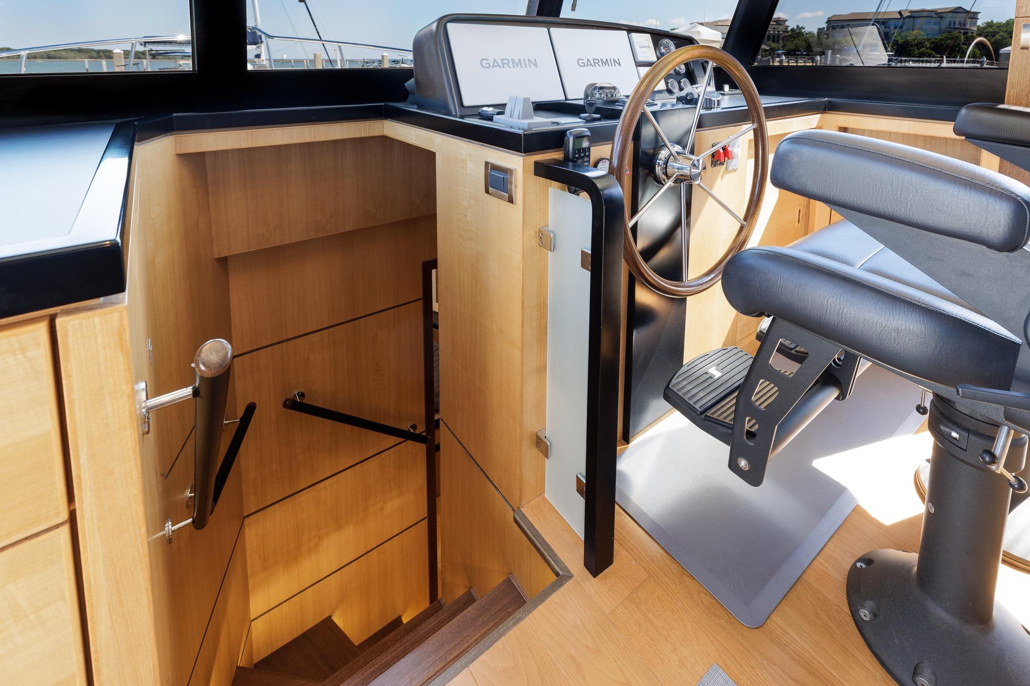 2023 North Pacific 49 Euro yacht helm with wooden steering wheel and staircase.