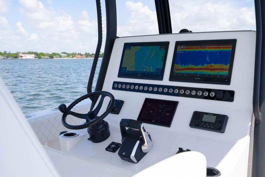 Control panel of 2027 Reef Runner 340 boat with navigation screens and steering wheel.