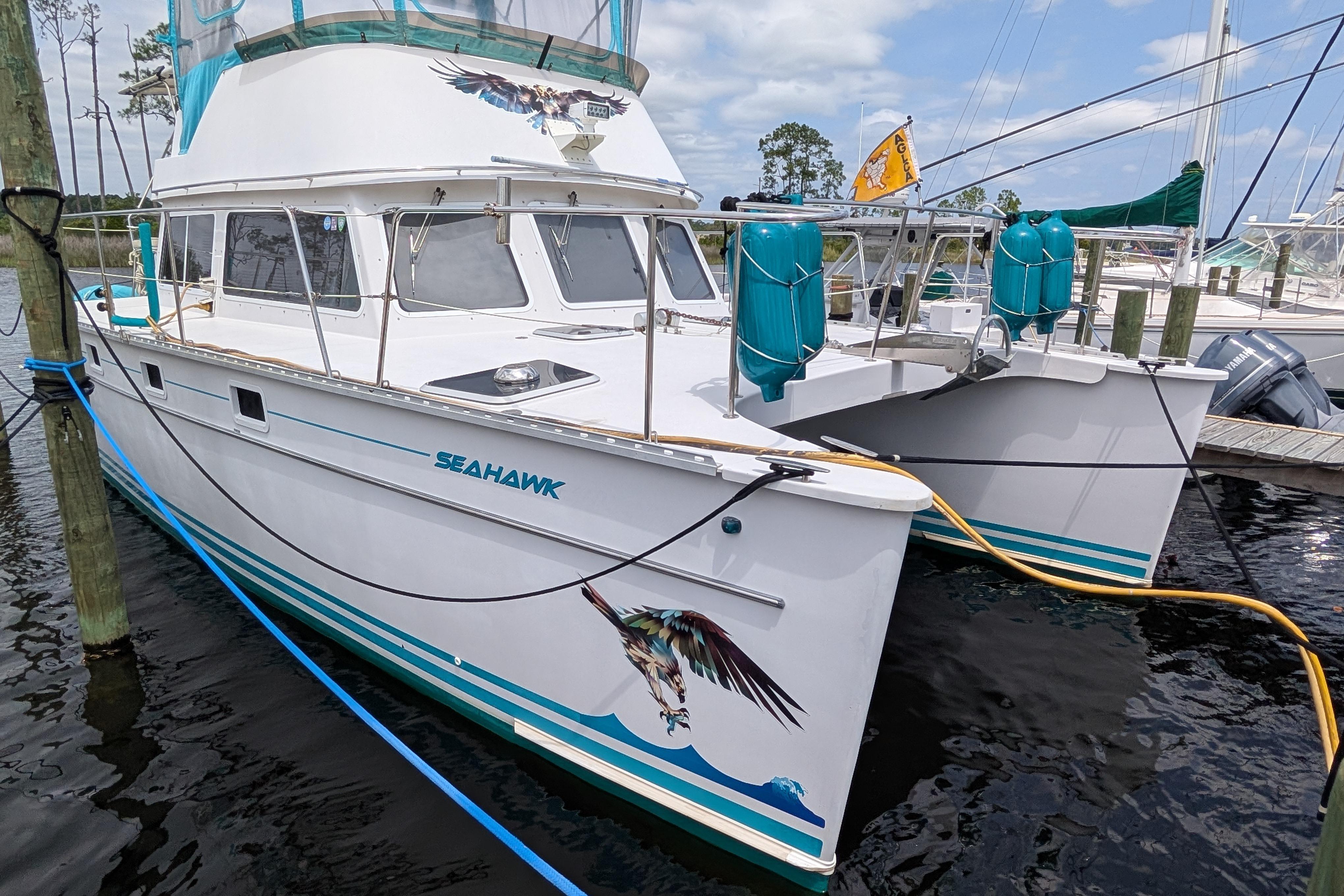 2004 PDQ 34 Power Catamaran "Sea Hawk" docked, featuring vibrant marine artwork.