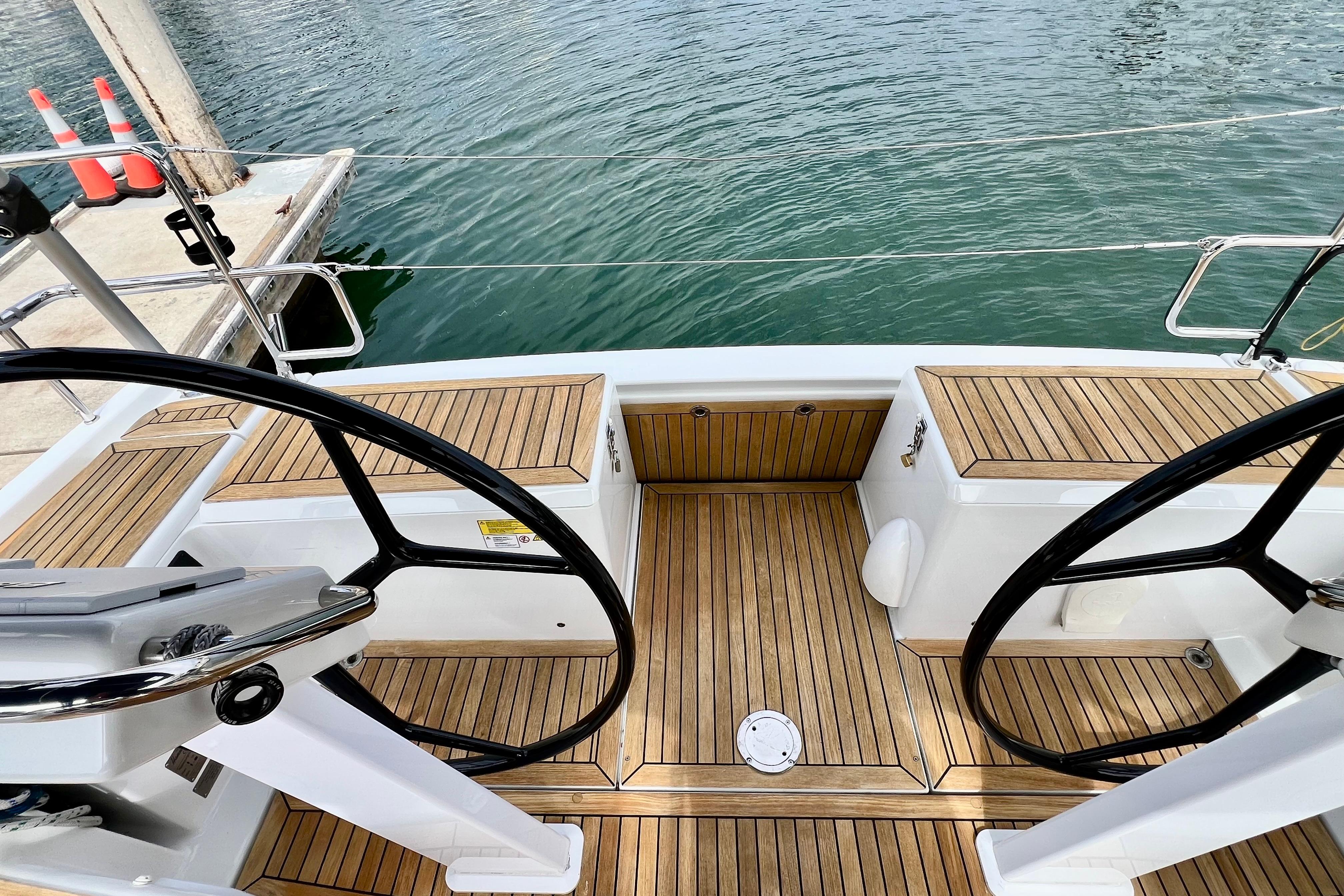 Cockpit of 2016 Hanse 455 sailboat with dual steering wheels and teak flooring.