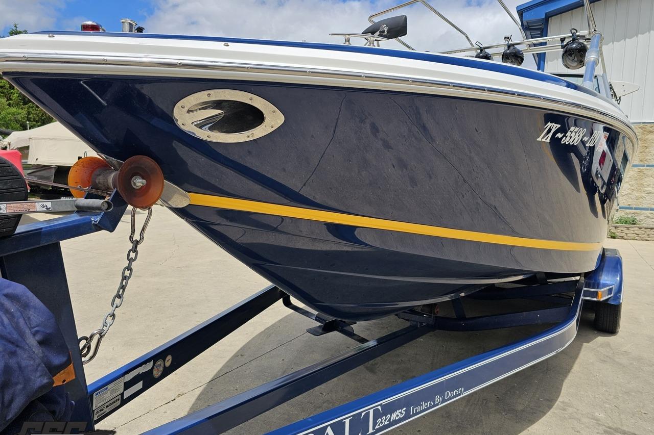 2010 Cobalt 232 WSS boat on trailer, blue hull with yellow stripe, parked outdoors.