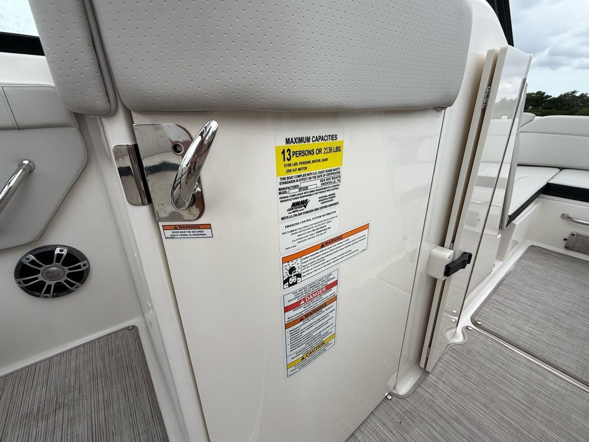The 2024 Sea Ray SPX 230 Outboard features a door with a capacity notice for 13 people.